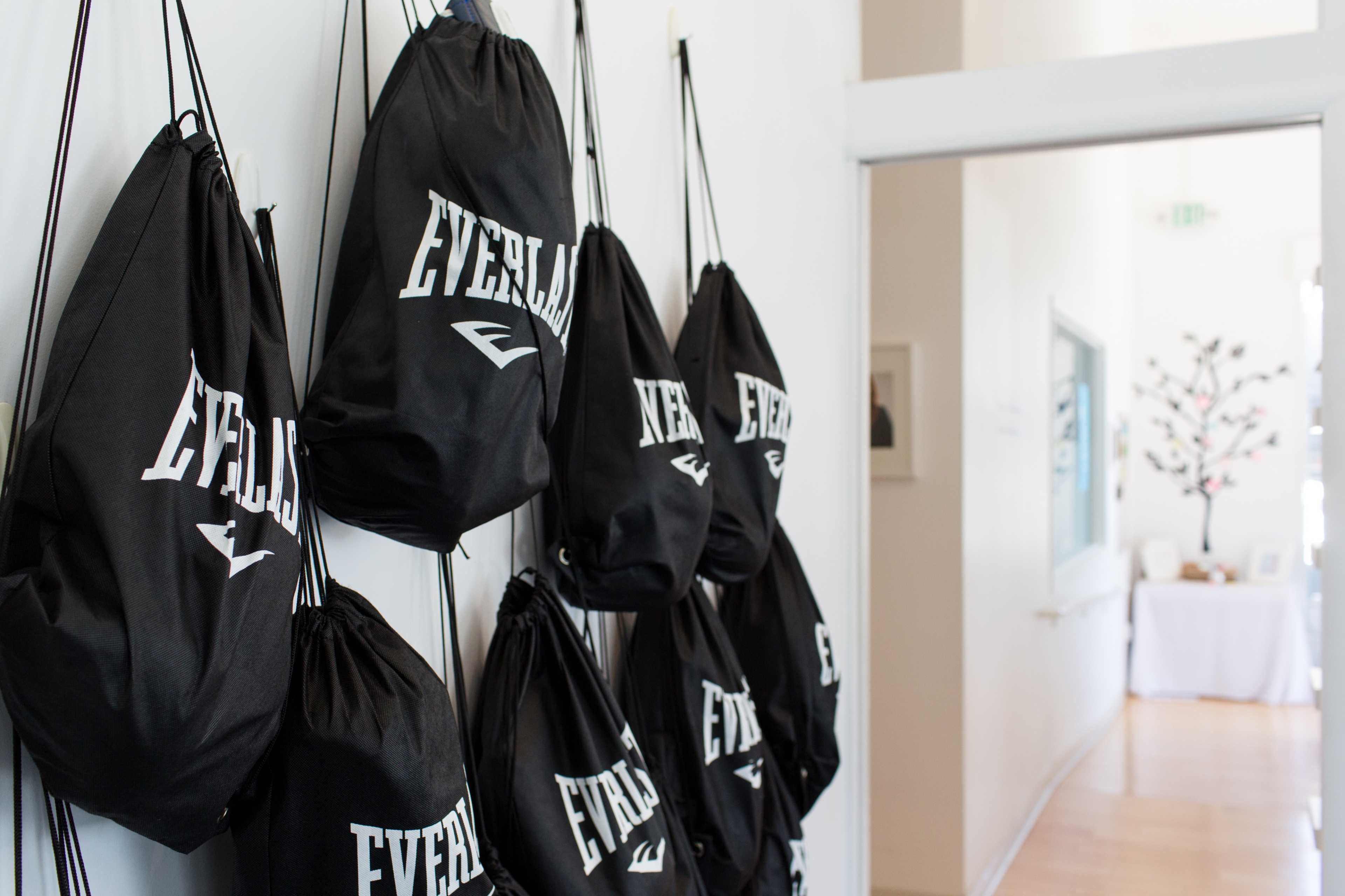 A row of black drawstring bags marked with the word "EVERLAST" hangs on a white wall.