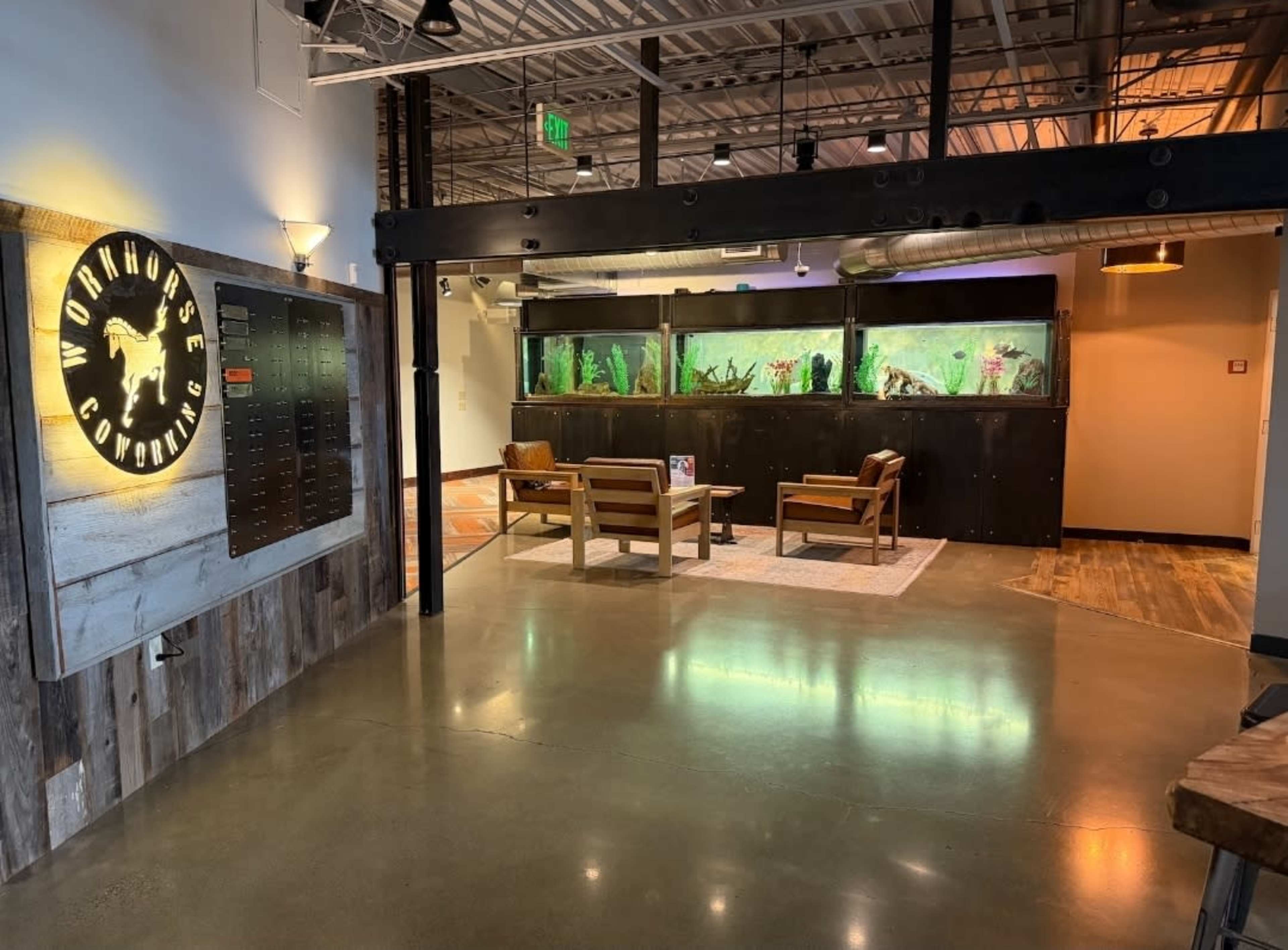 The image shows a modern interior space featuring a reception area with wooden furniture and a large aquarium in the background.