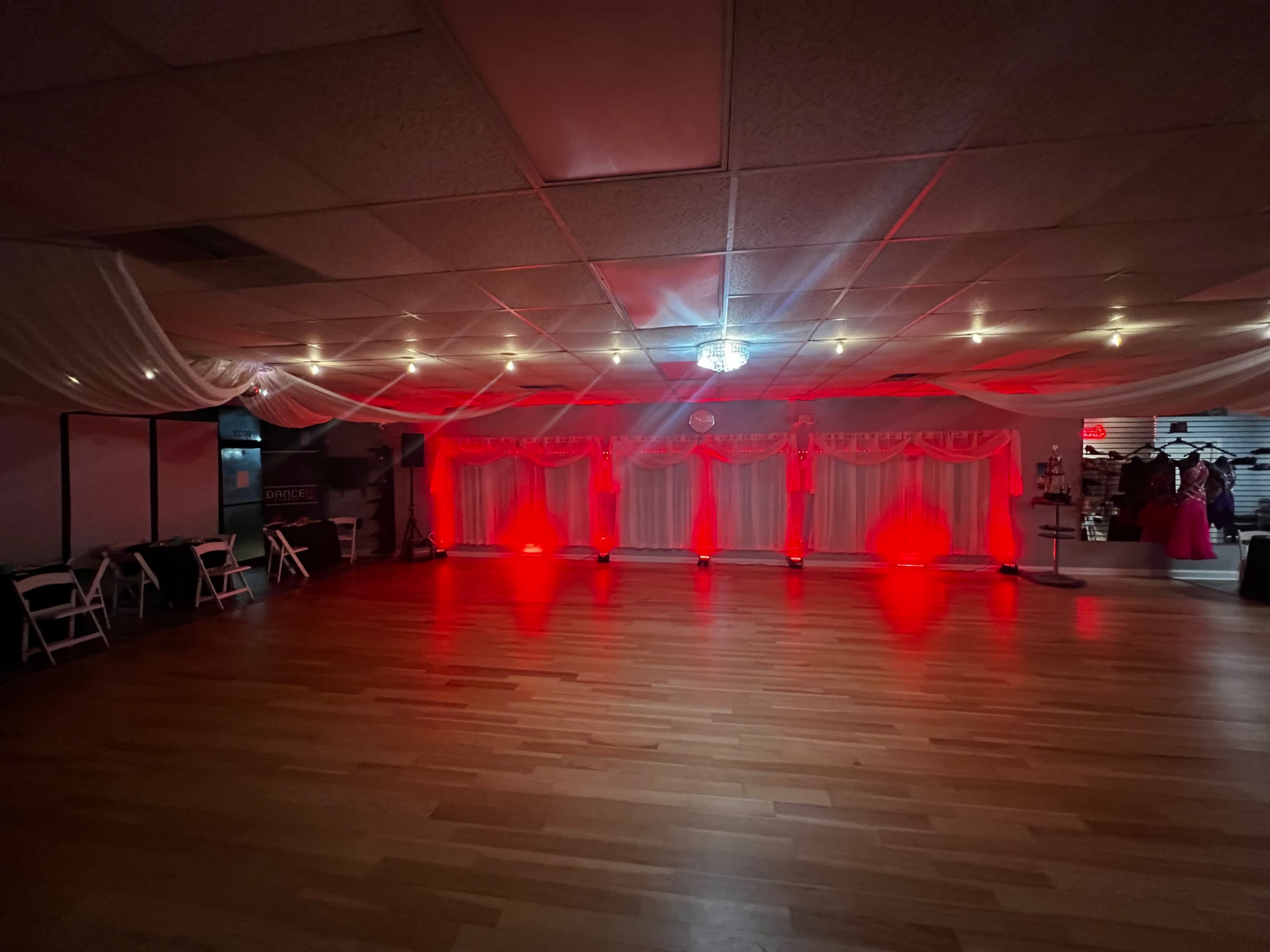 A dance floor decorated with red lighting and draped fabric in a spacious venue.