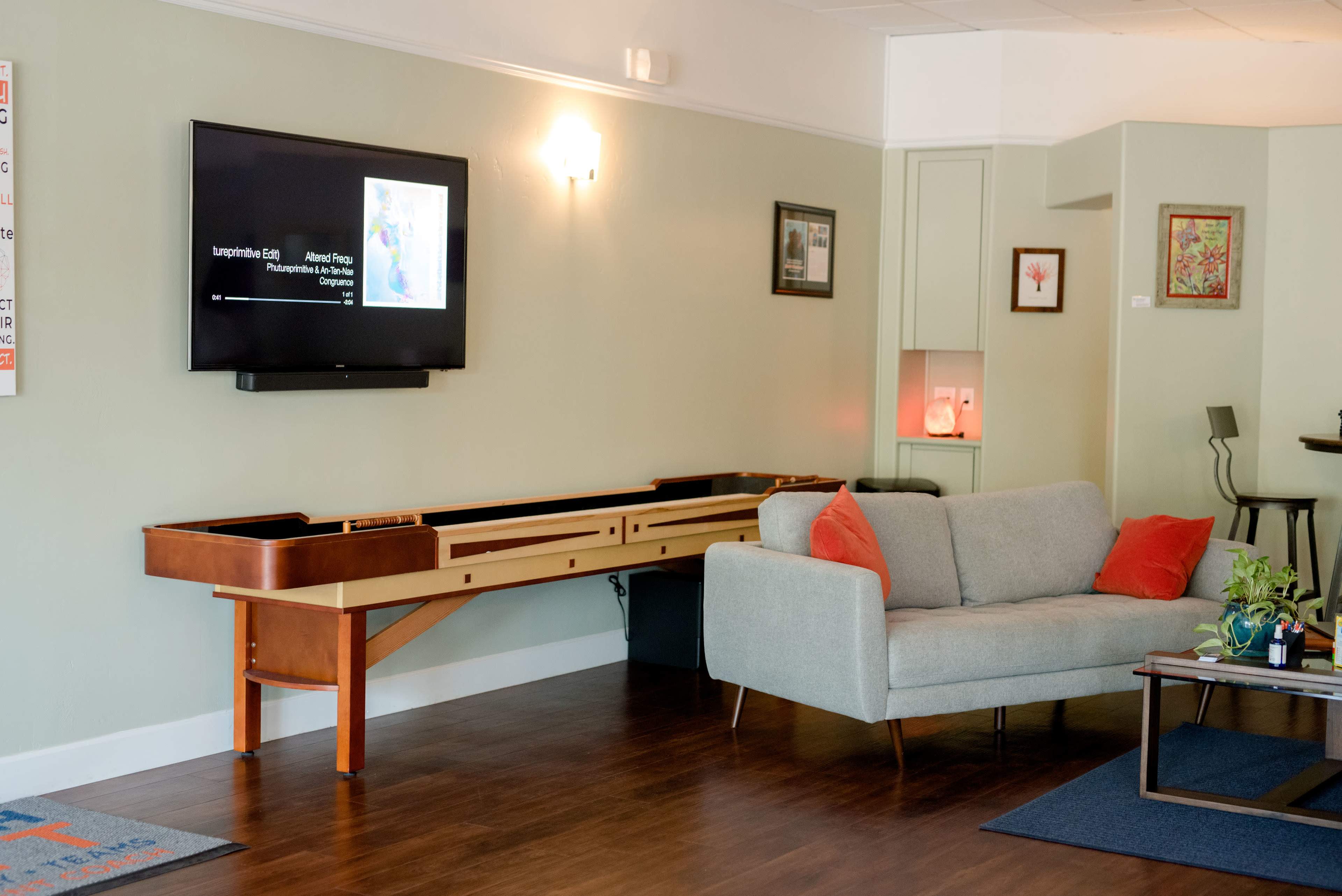 A modern living space with a gray sofa, a long wooden console underneath a television, and a small table in the background.