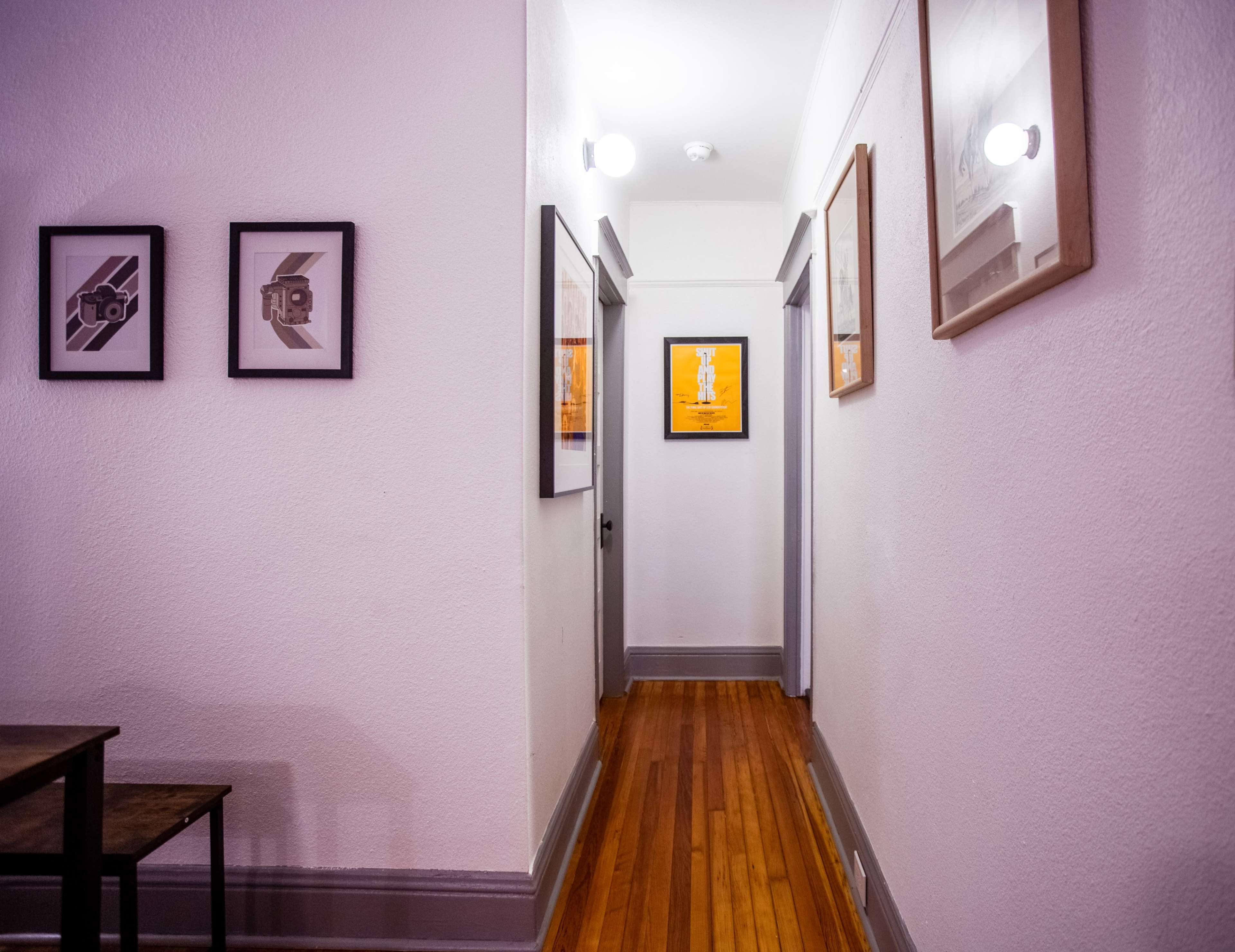 A narrow hallway features framed artwork on the walls and wooden flooring.