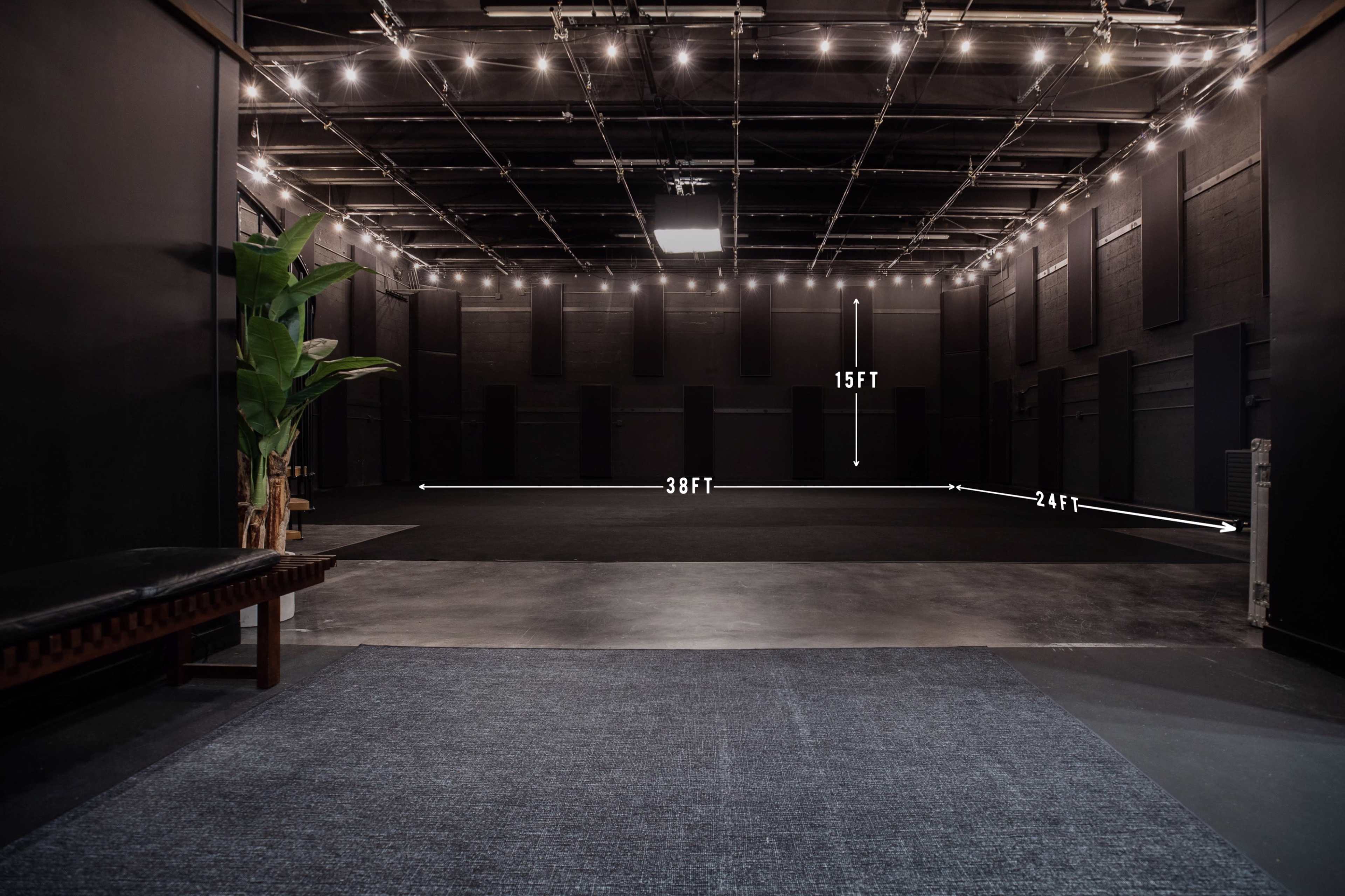The image shows a spacious recording studio or performance space with a total area of 38 feet by 24 feet and a height of 15 feet, illuminated by overhead lights.