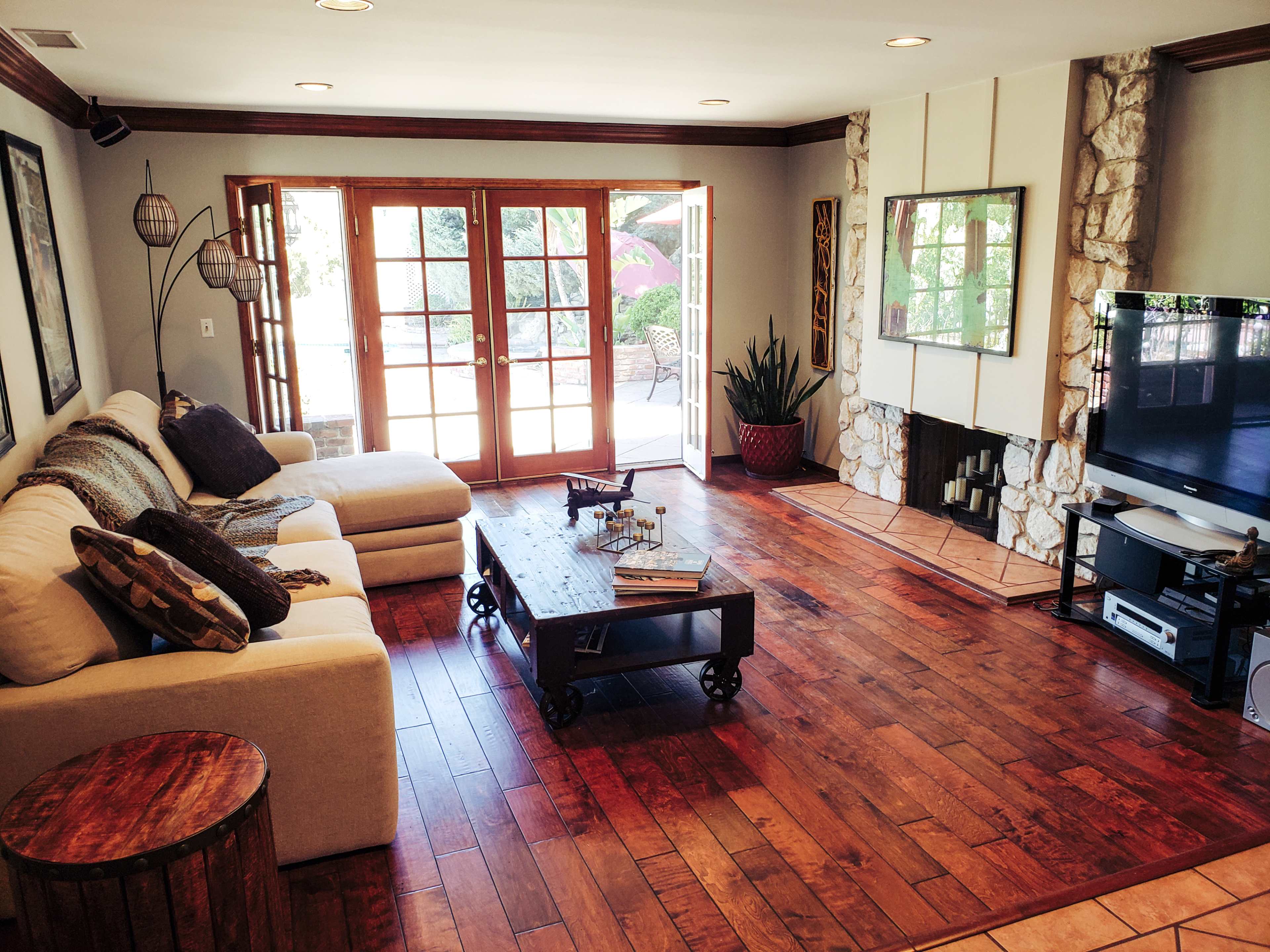 The room features a cozy living area with a sectional sofa, a wooden coffee table, and large glass doors leading to an outdoor patio.