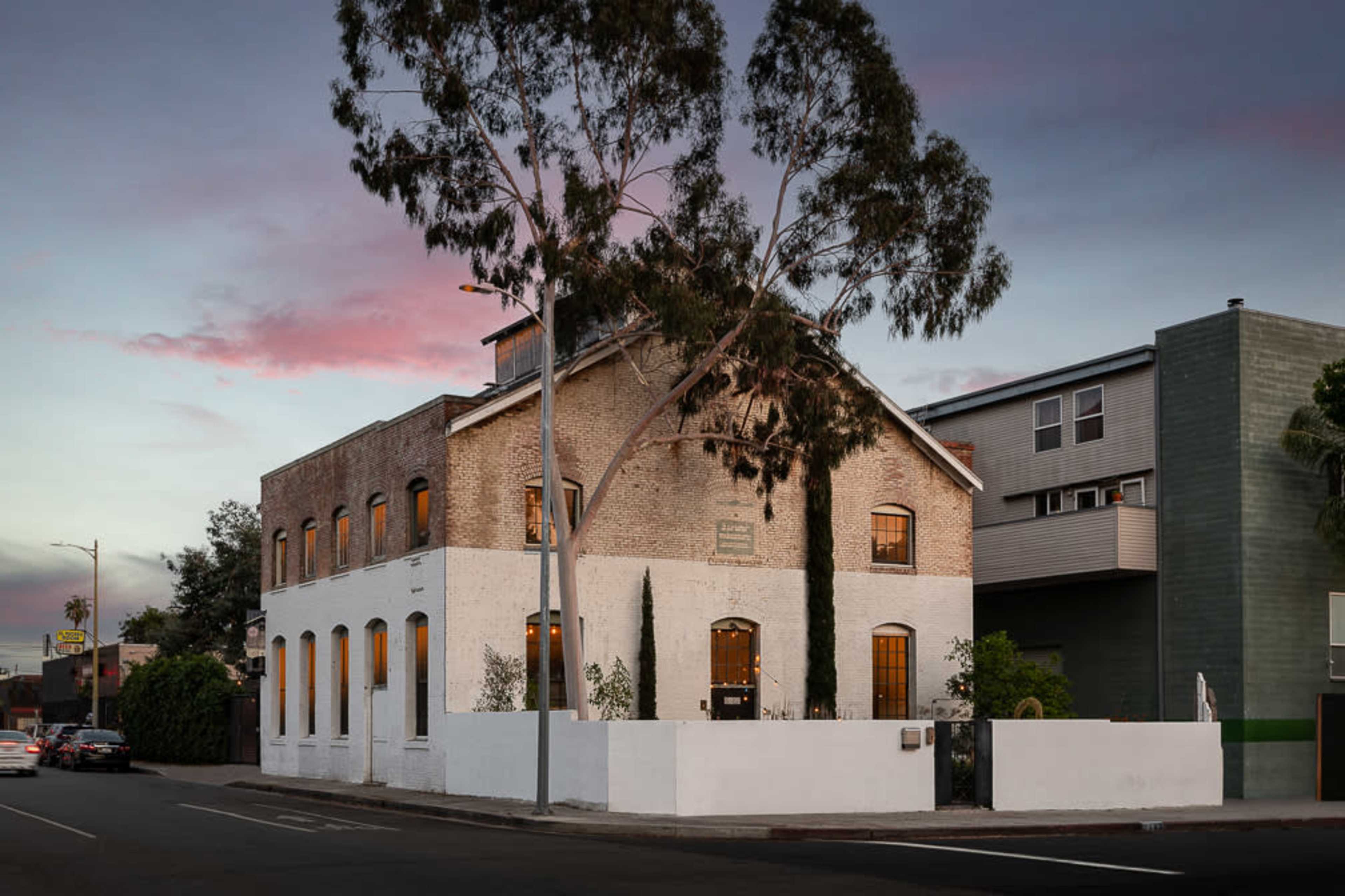 A two-story building with a brick facade and white accents stands at the corner, surrounded by trees and residential structures.