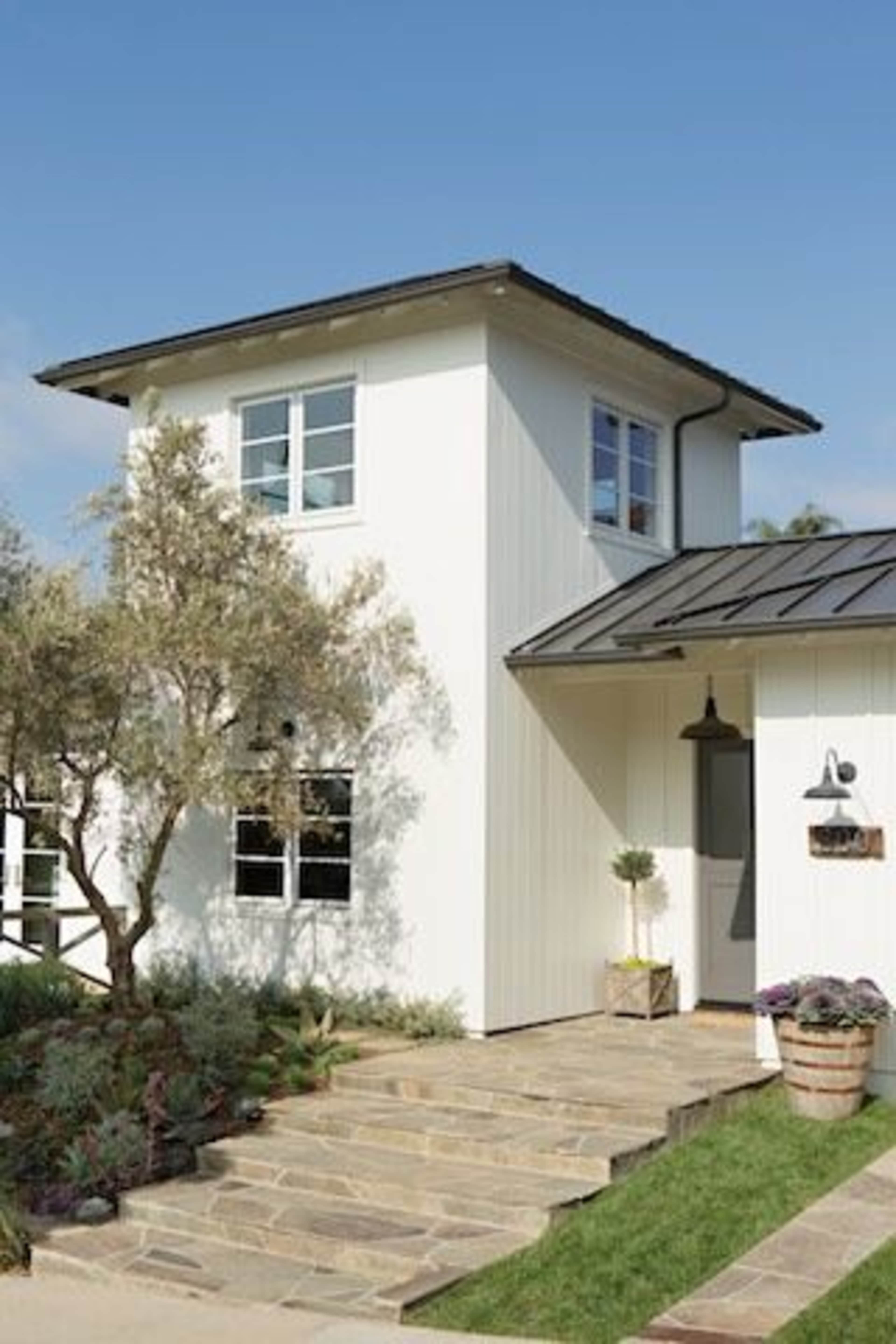 A modern two-story white house with large windows and a stone pathway leading to the entrance.