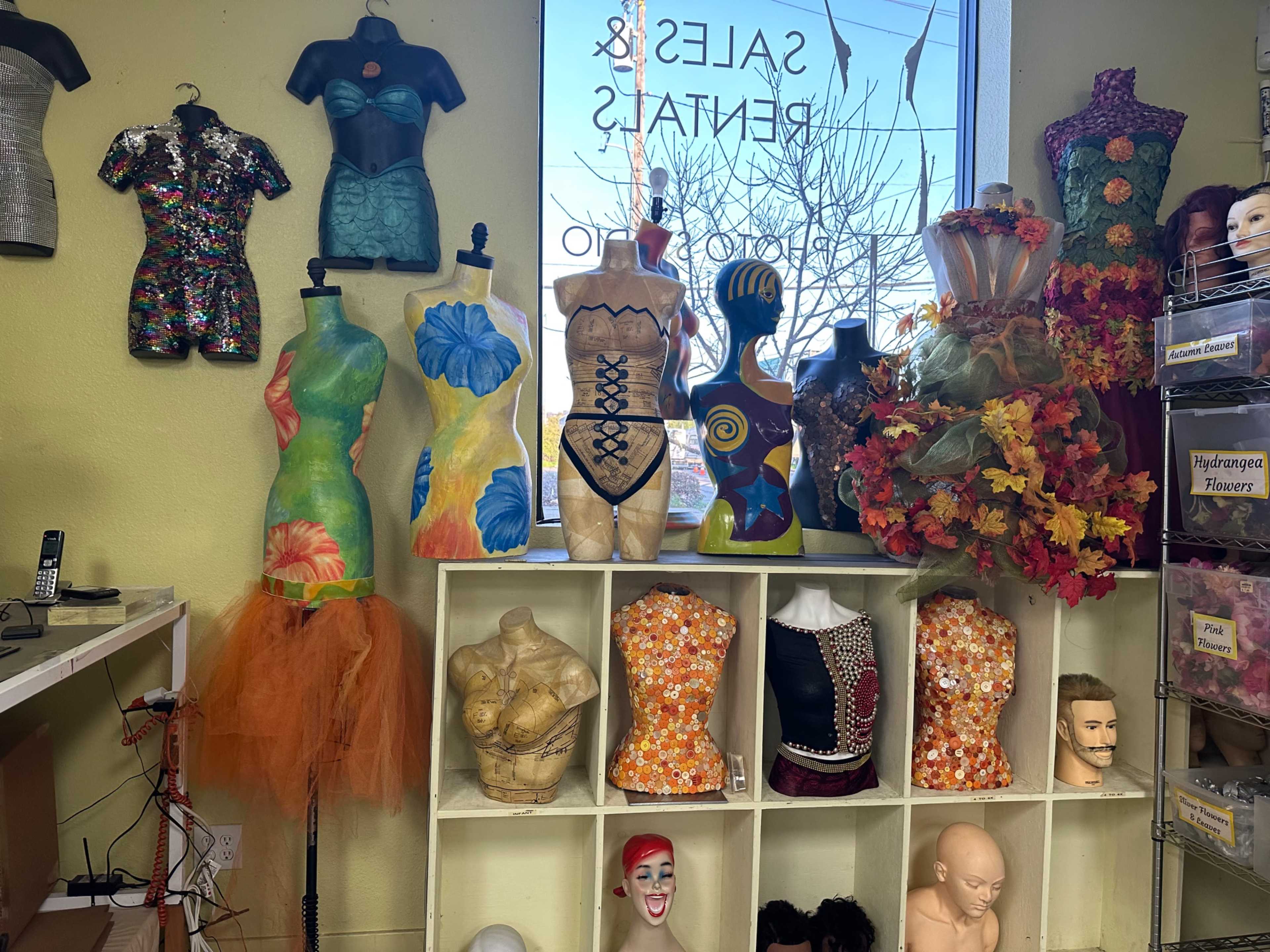 The image shows a display of colorful mannequins and decorative accessories arranged on a shelf in a boutique.