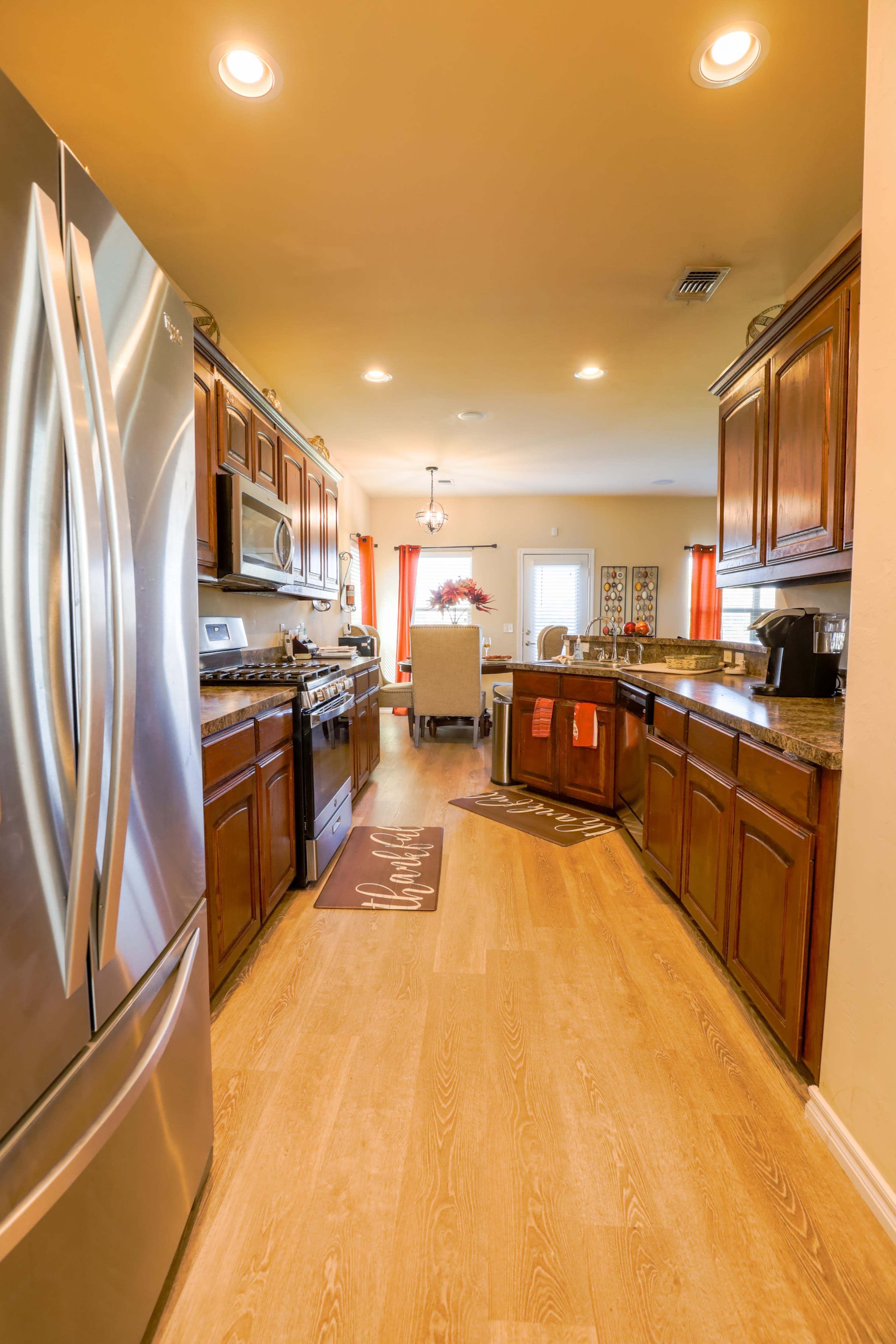 A modern kitchen with stainless steel appliances, wooden cabinets, and a light-colored floor.