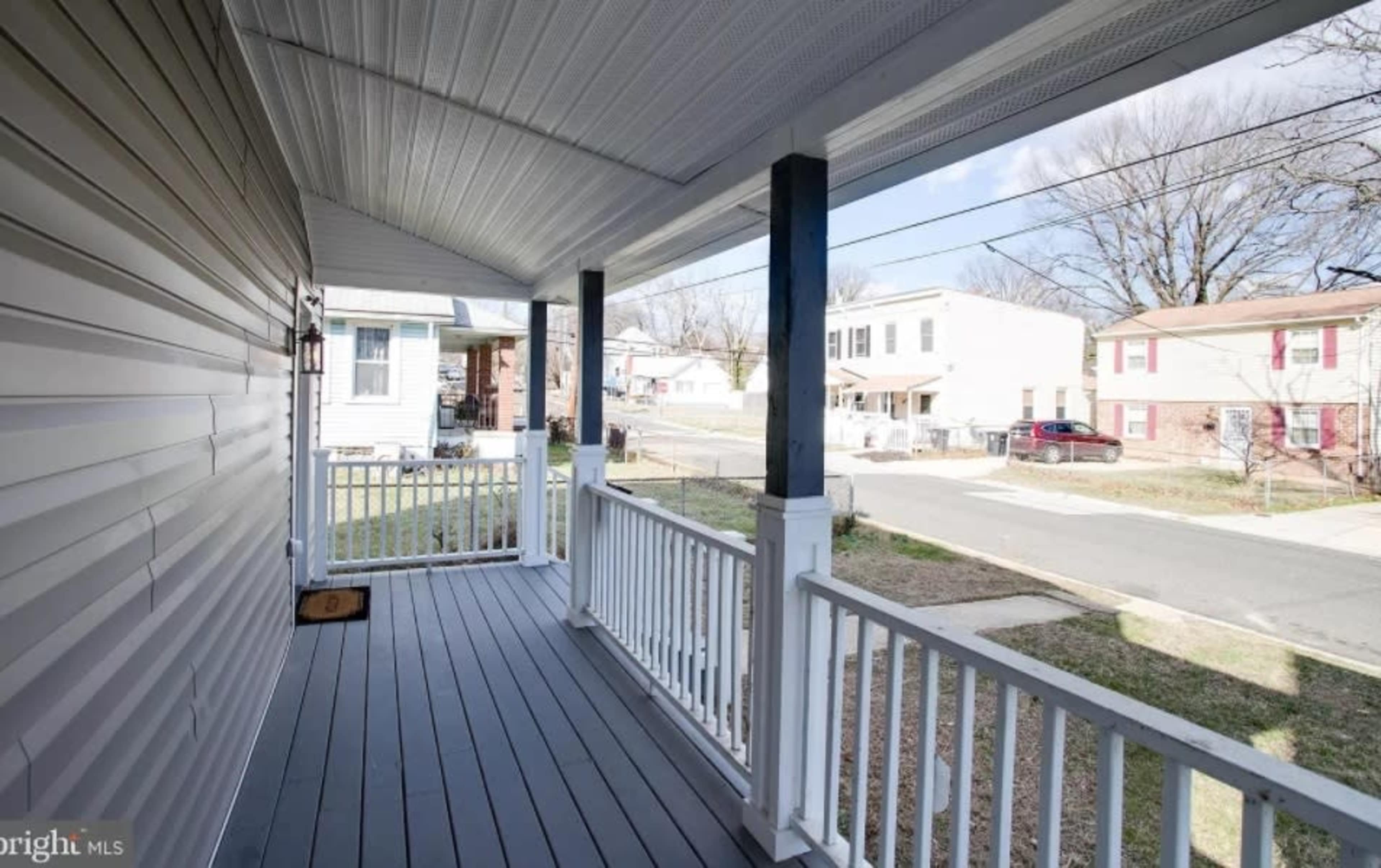 A covered porch with a view of a residential street lined with houses.