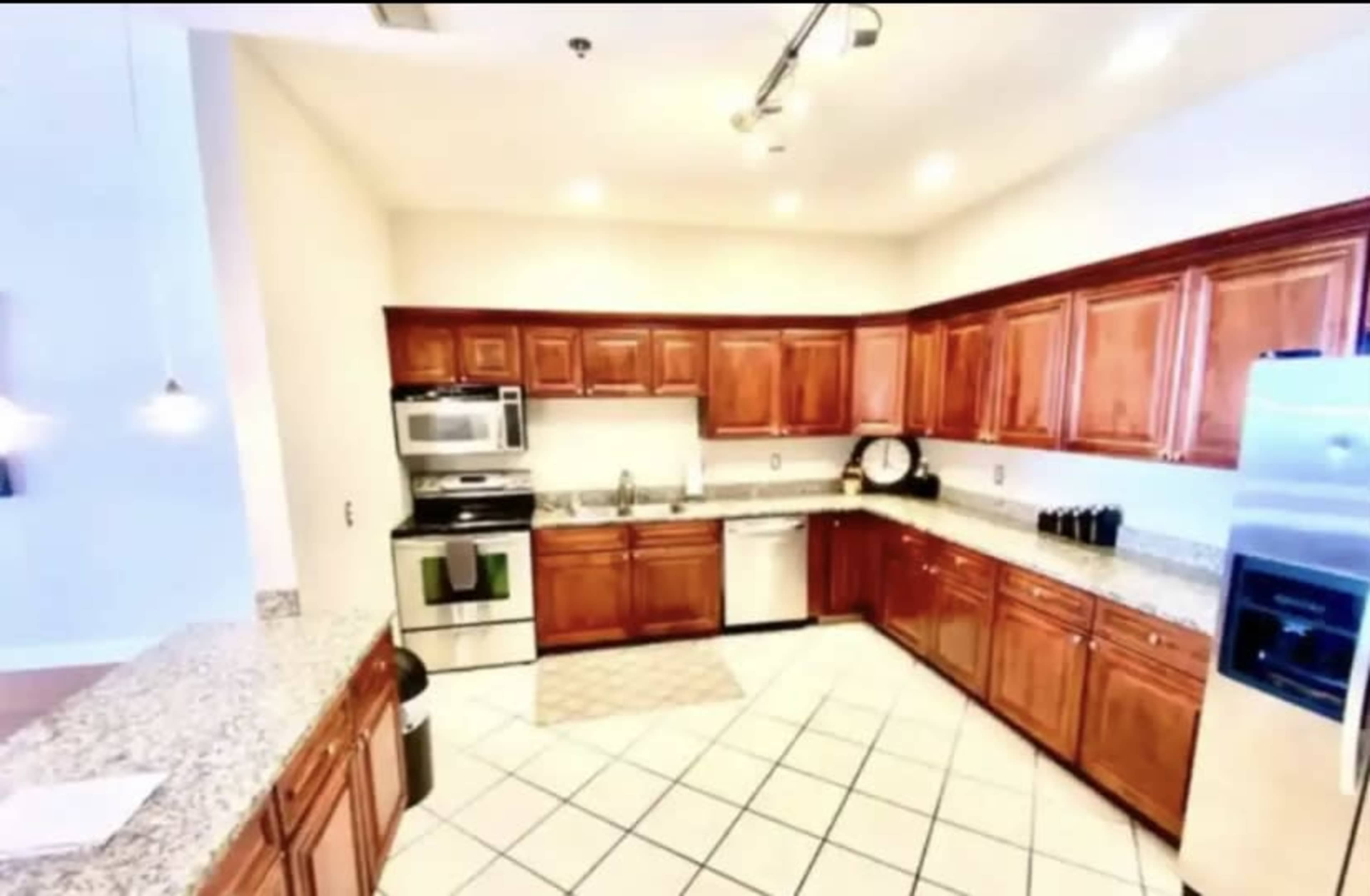 The image depicts a kitchen with wooden cabinets, granite countertops, and stainless steel appliances arranged in a U-shape.
