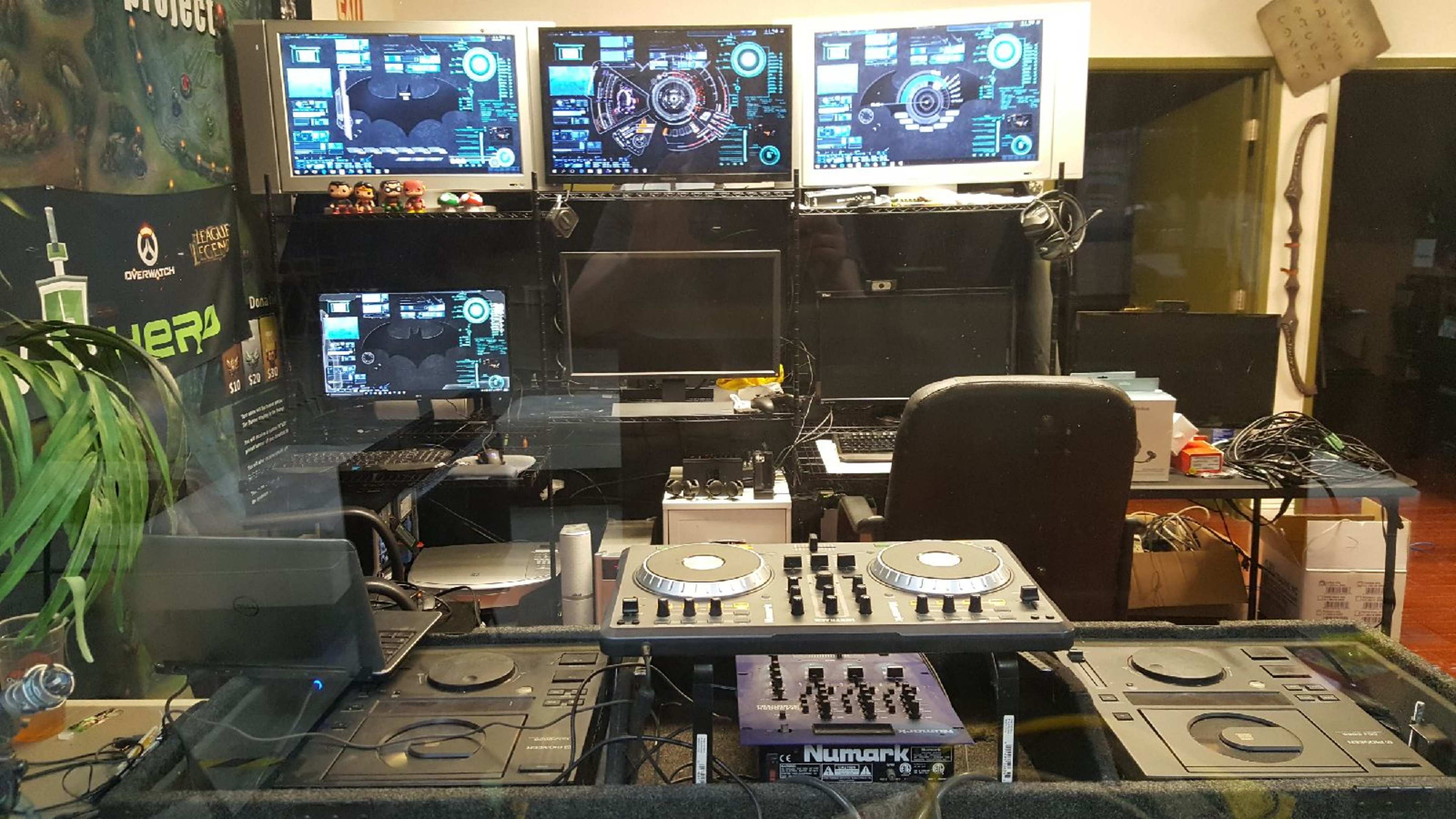 A gaming setup featuring multiple monitors displaying digital interfaces, with a DJ console prominently placed in the foreground.
