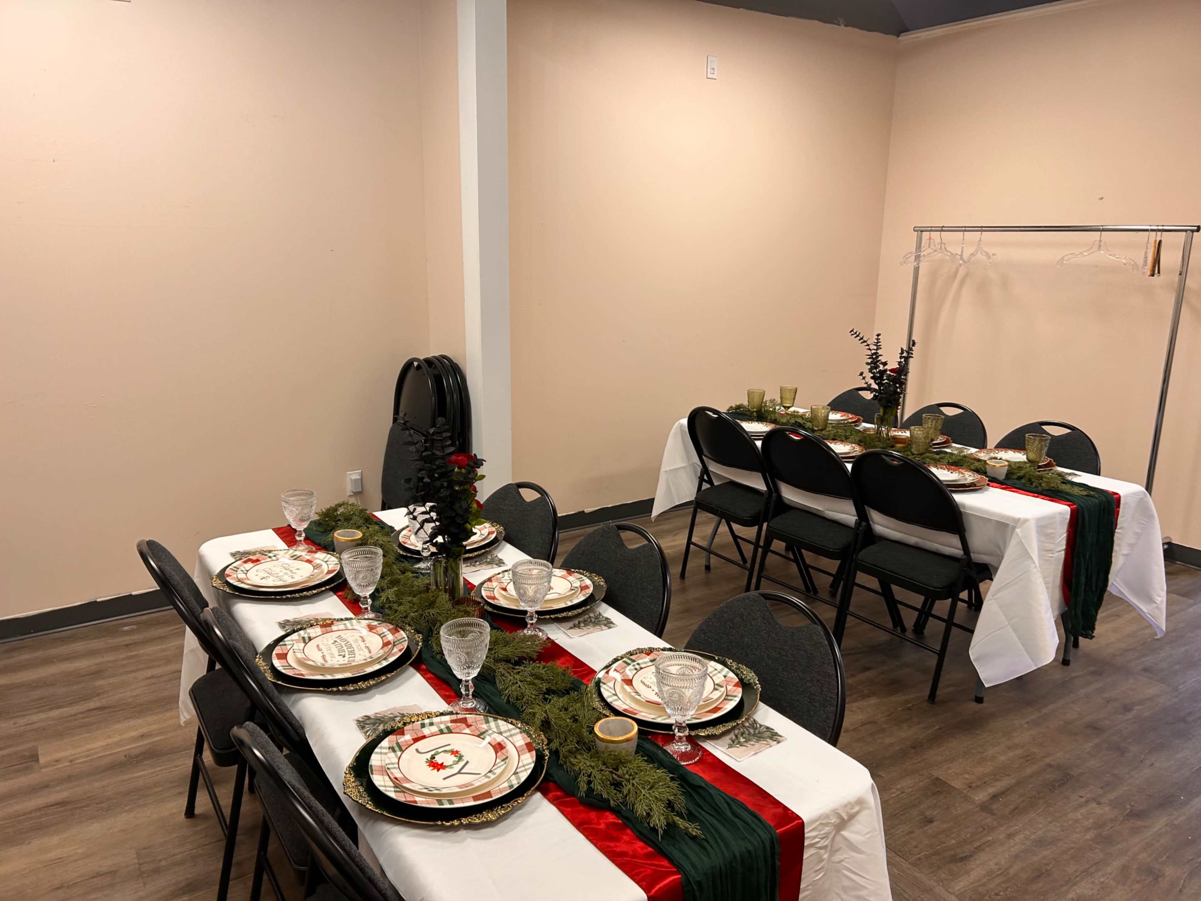 A dining area is set up with two long tables, each adorned with decorative tableware, green garlands, and red accents.