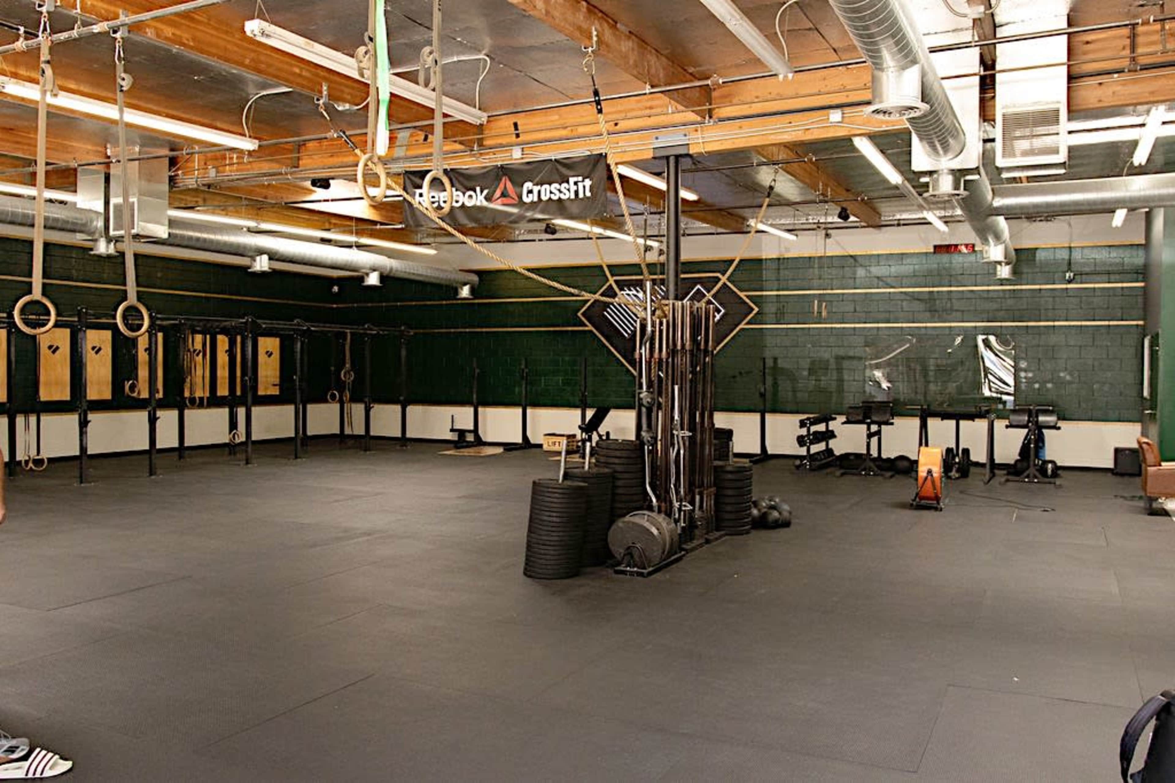 An empty CrossFit gym equipped with various workout stations and fitness equipment.