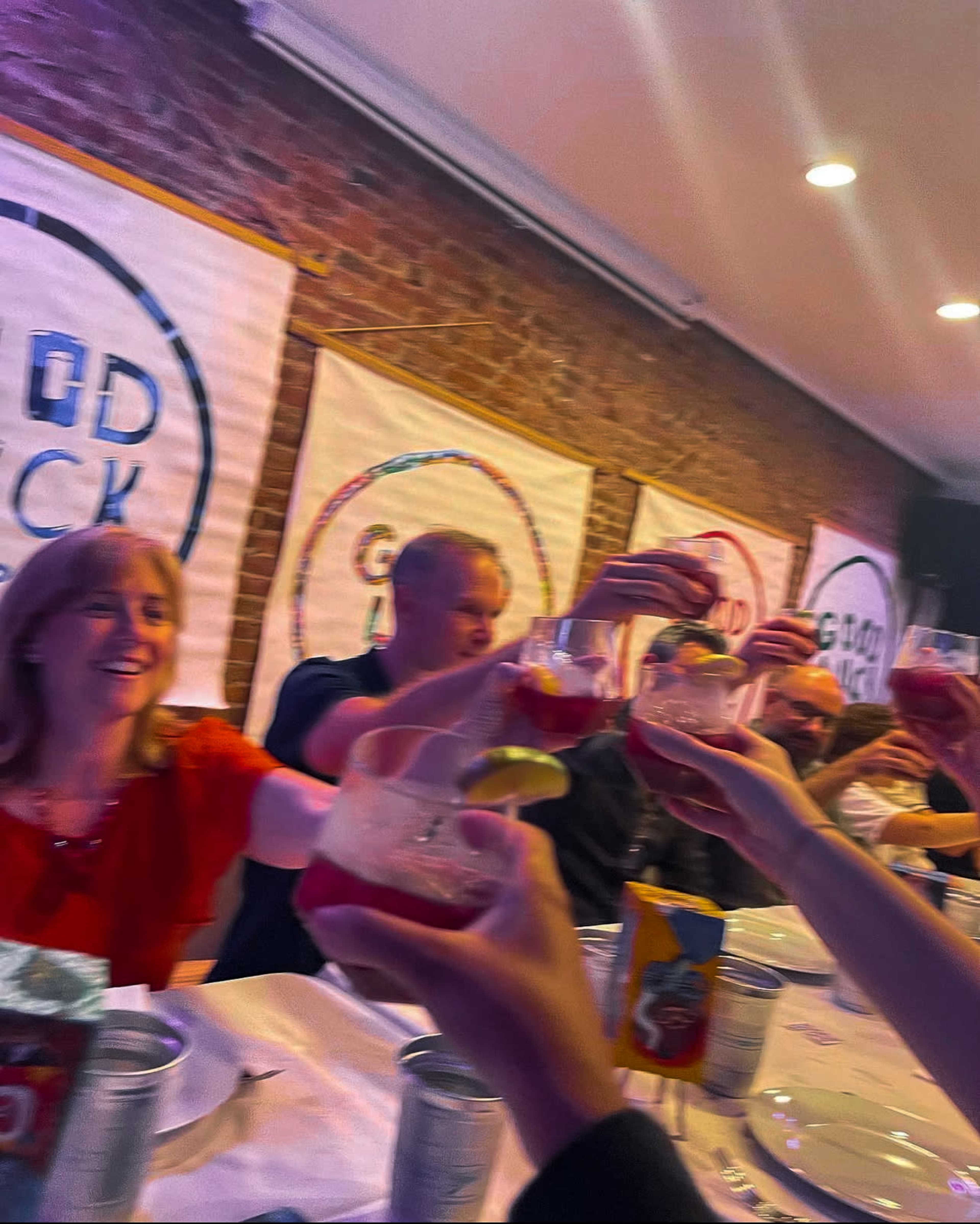A group of people is raising their glasses in a toast at a celebratory gathering around a table.