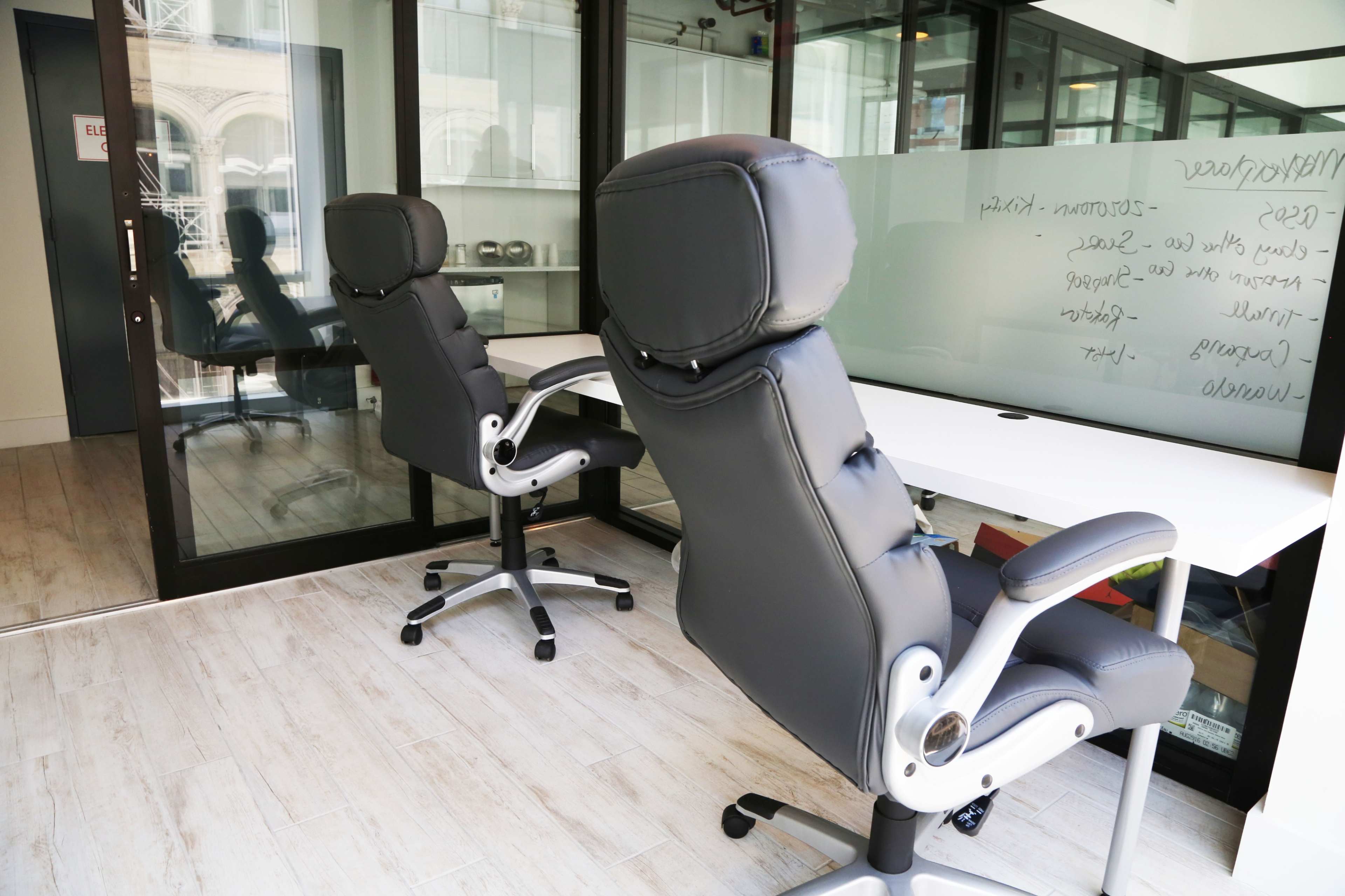 Two ergonomic office chairs positioned next to a minimalist white desk in a modern workspace.
