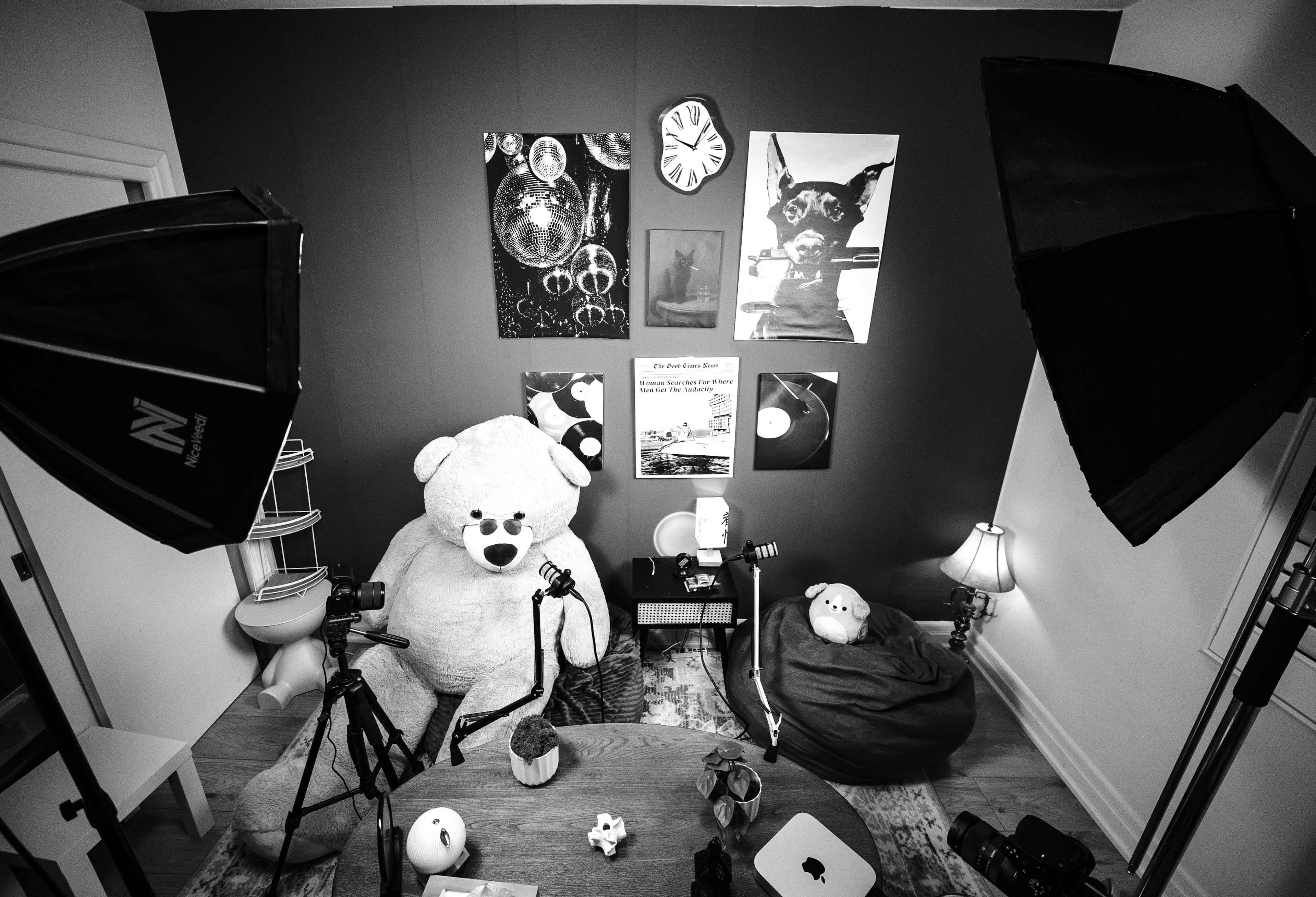 The scene features a cozy room with a large teddy bear, a round table, and various decorations, including framed pictures and lamps, all arranged under studio lighting.