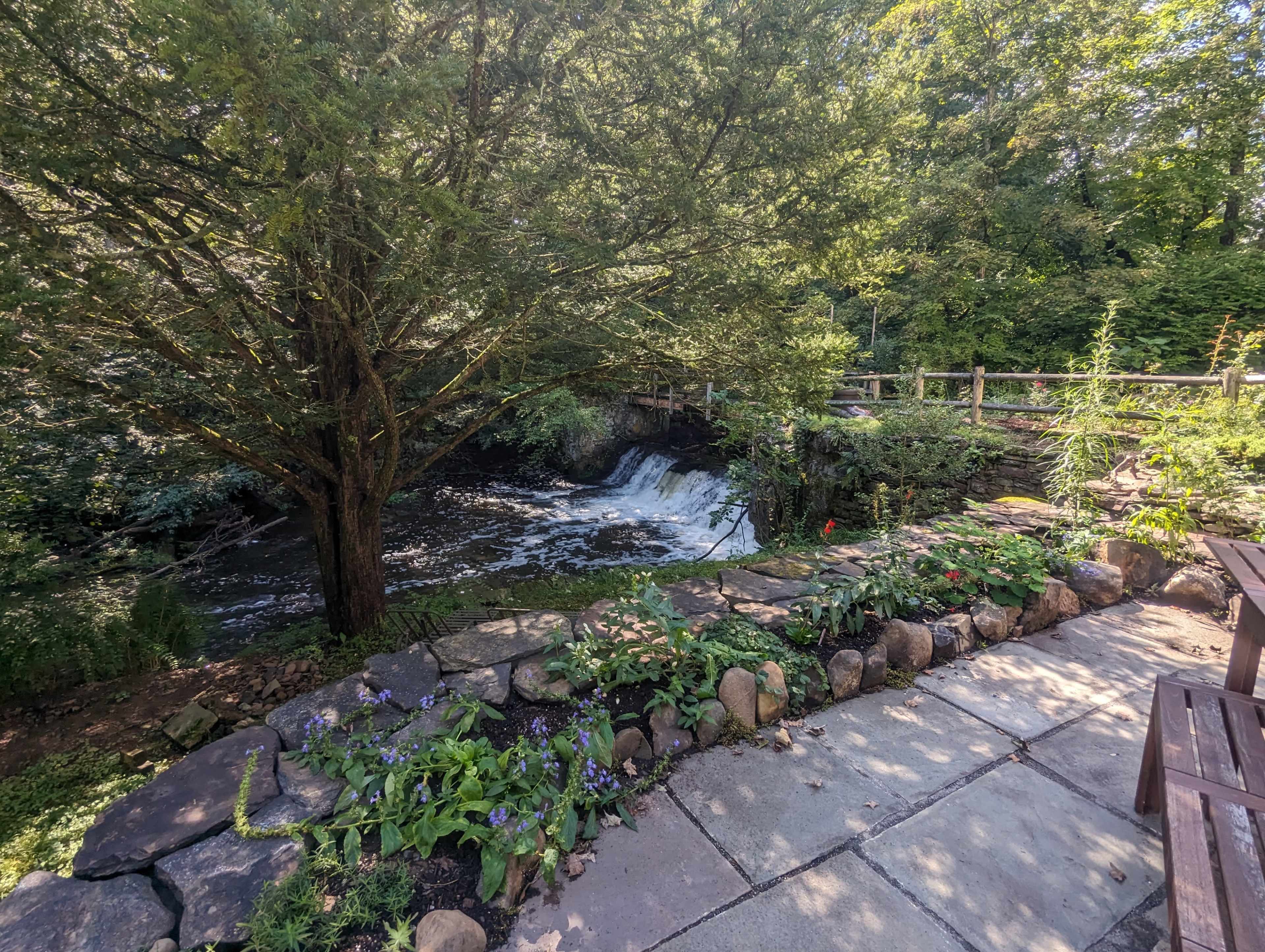 A stone-lined patio overlooks a cascading waterfall surrounded by lush greenery.