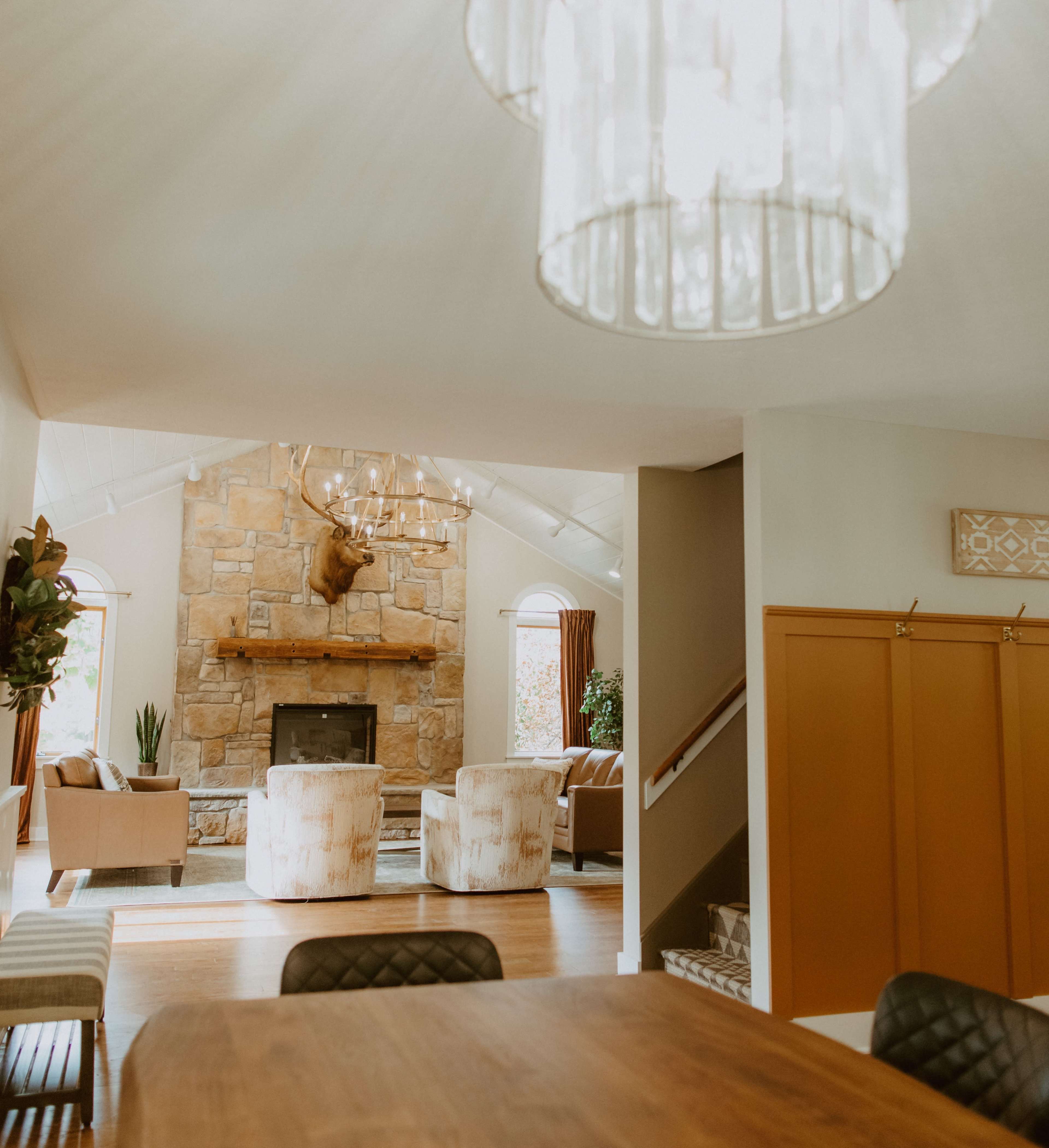 A living room with a stone fireplace, two armchairs, and a dining area with a wooden table.