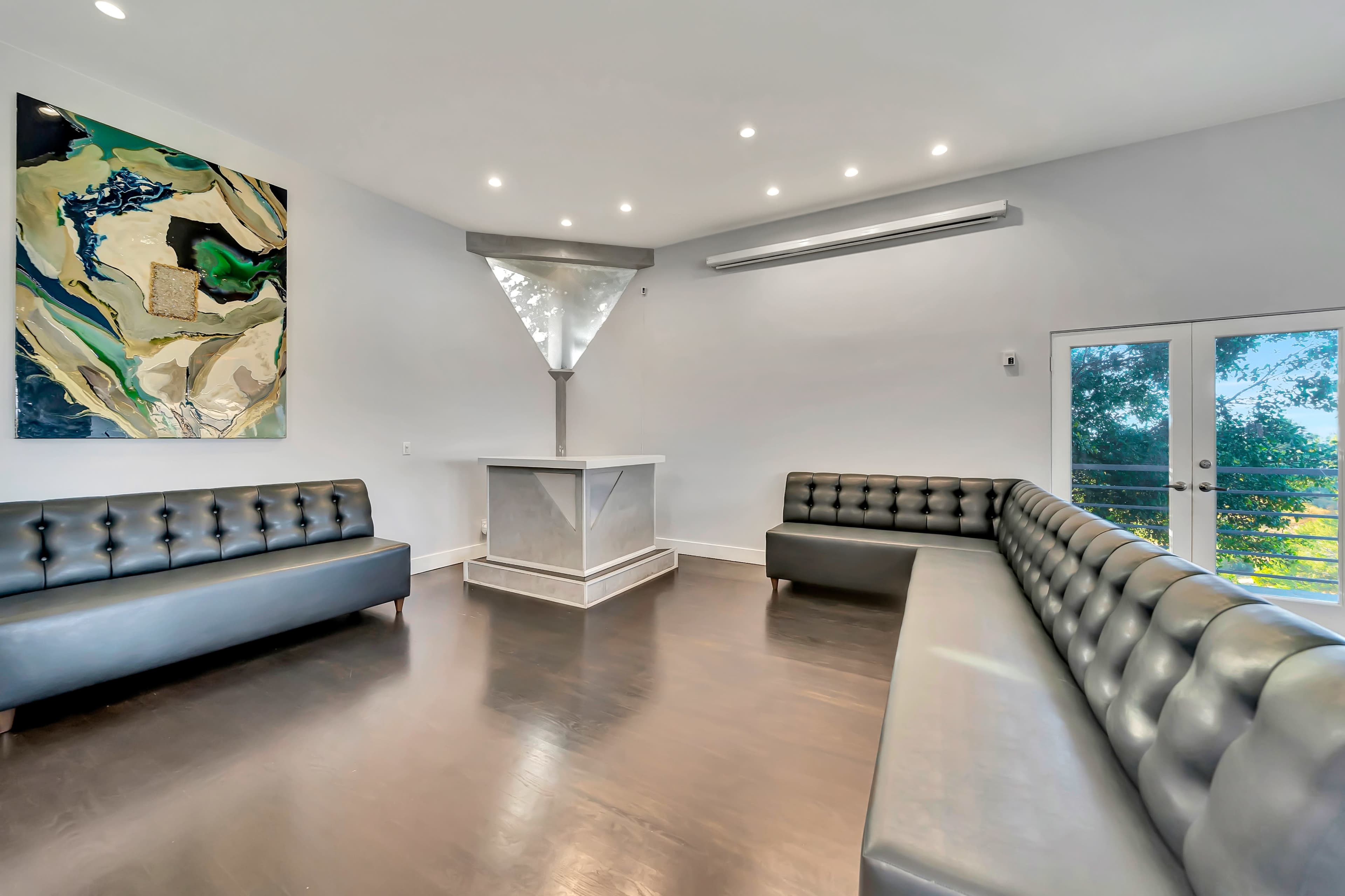 A modern, minimalist waiting area with two dark sofas positioned along the walls and a central geometric table.