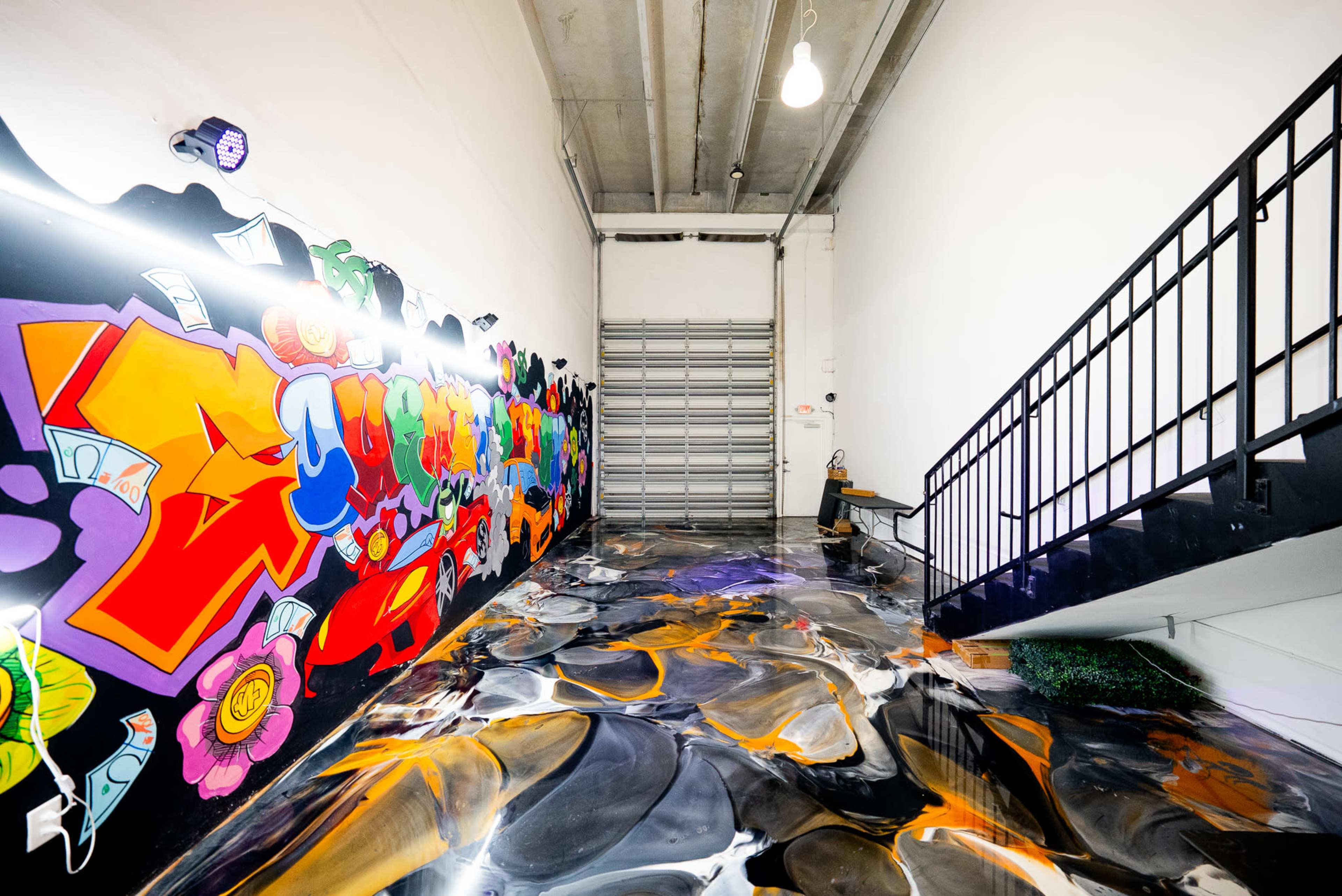 The image shows a brightly colored graffiti wall alongside a staircase in a space with a glossy, marble-effect floor.