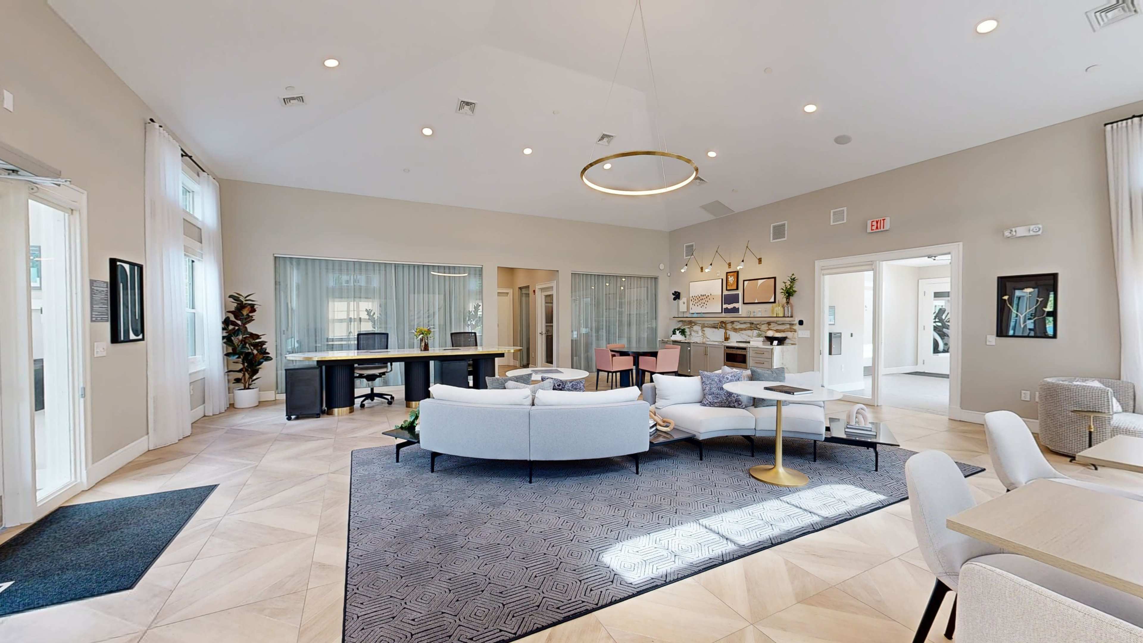 The image shows a spacious, well-lit lobby area featuring seating arrangements, a reception desk, and large windows allowing natural light to enter.