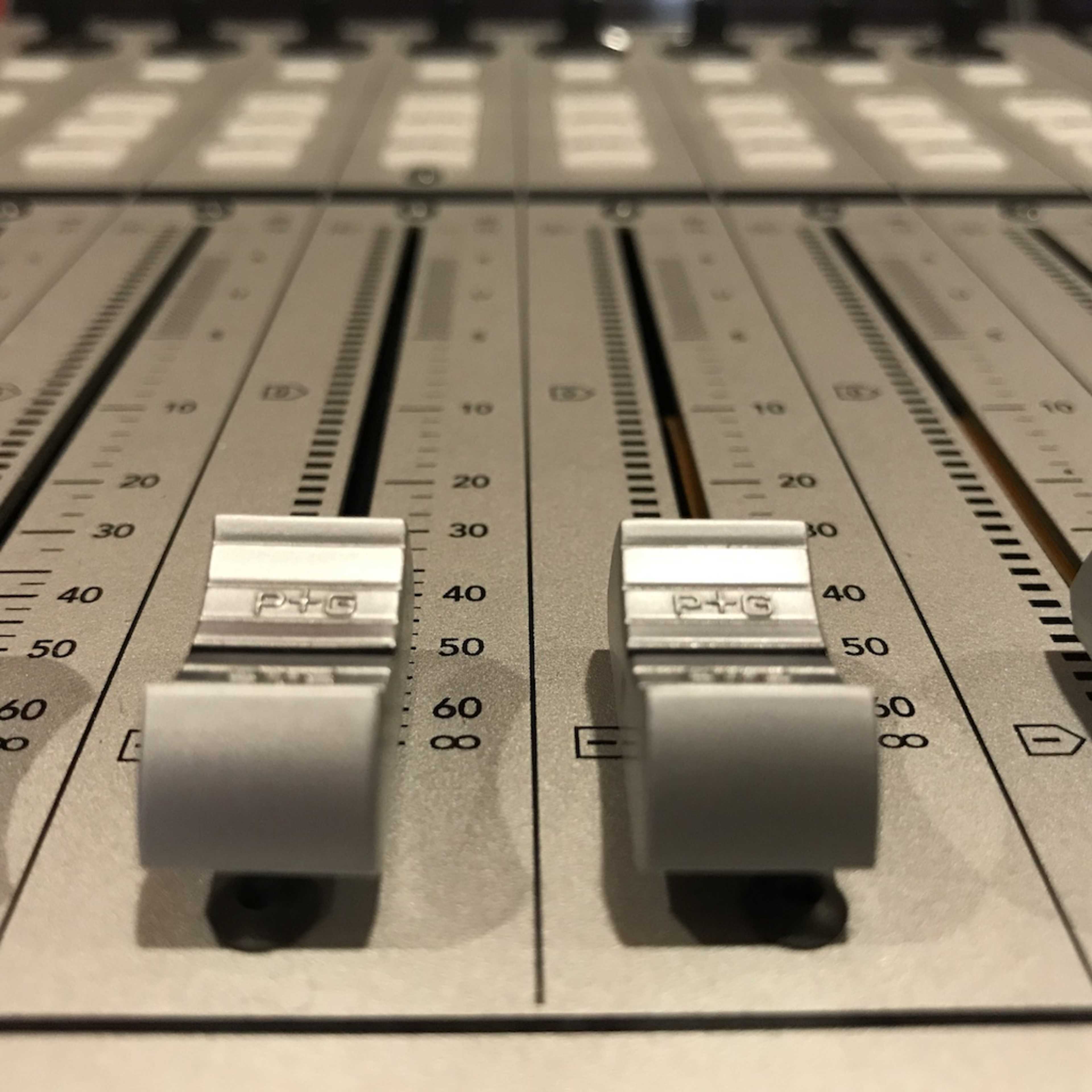 A close-up view of audio mixing sliders on a soundboard.