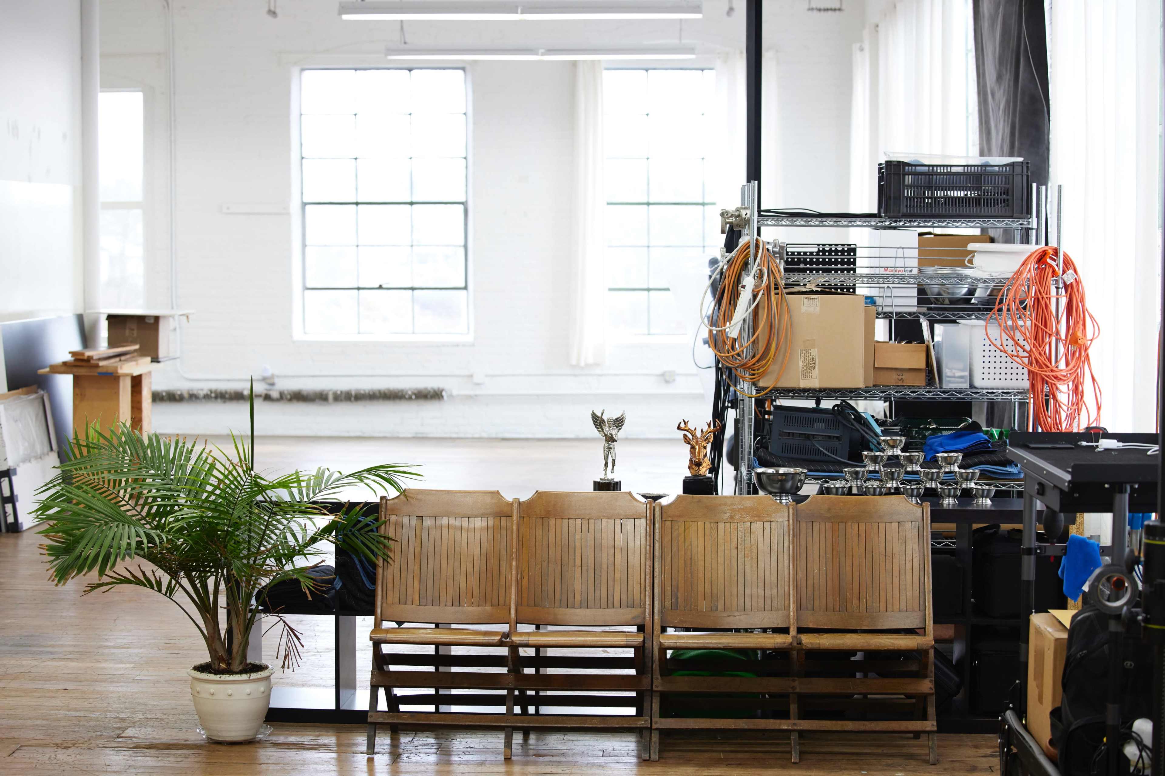 A bright, open interior space with wooden chairs lined up in front of a shelf filled with various items, including trophies and equipment.