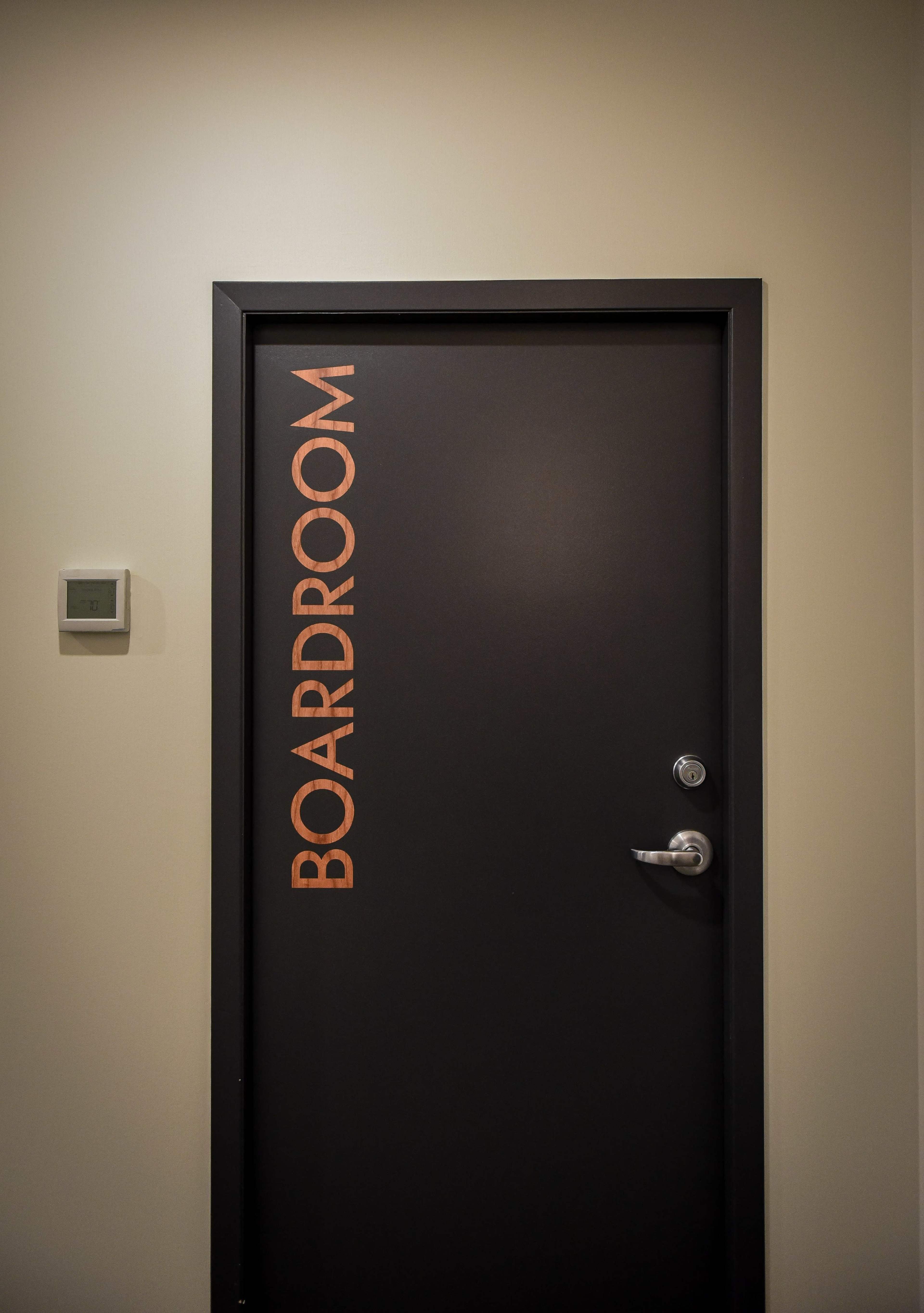 The image shows a closed black door labeled "BOARDROOM" in bold, capital letters on the right side.