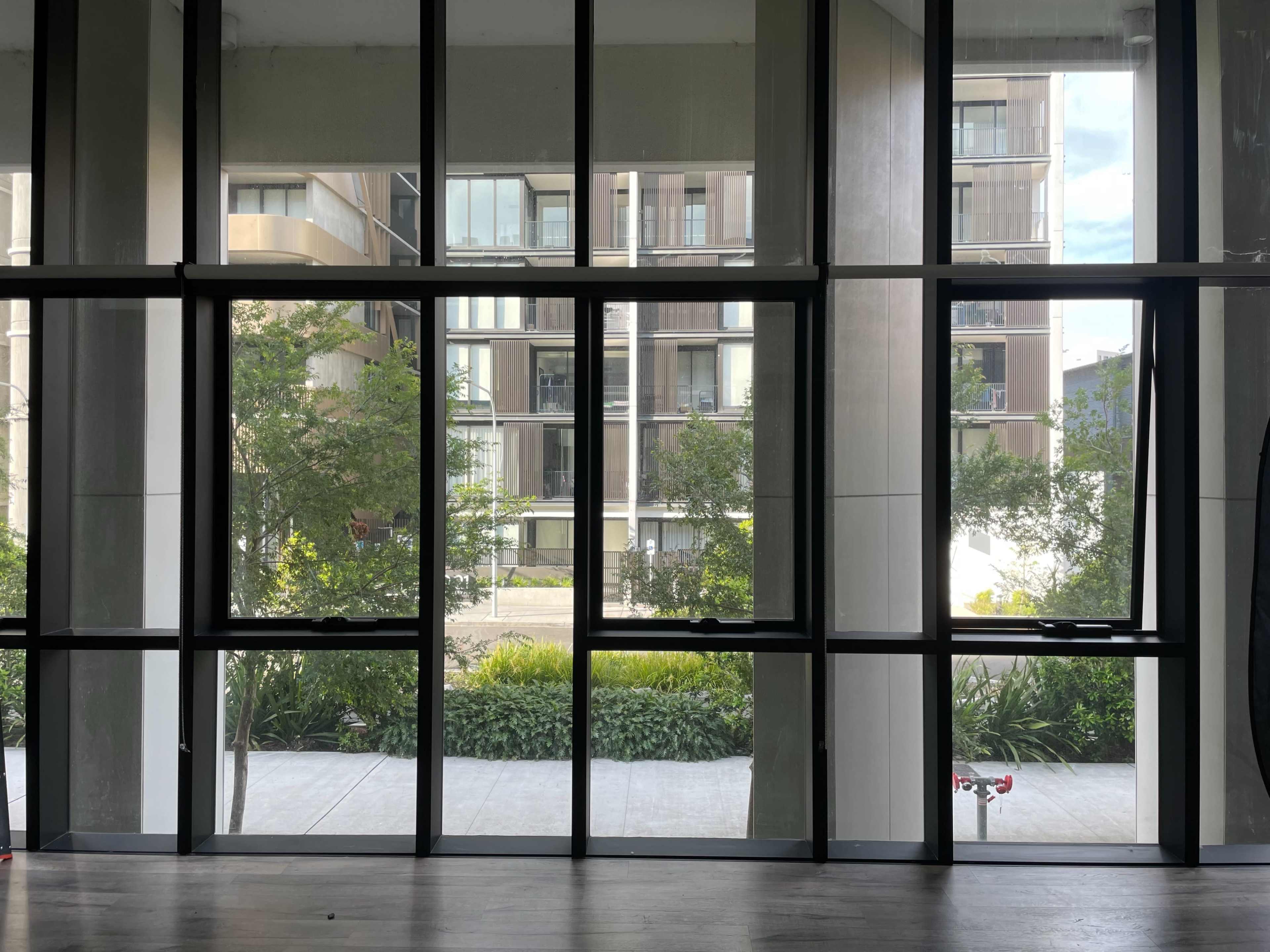 A large glass window frame with trees and buildings visible outside, set within a modern interior space.