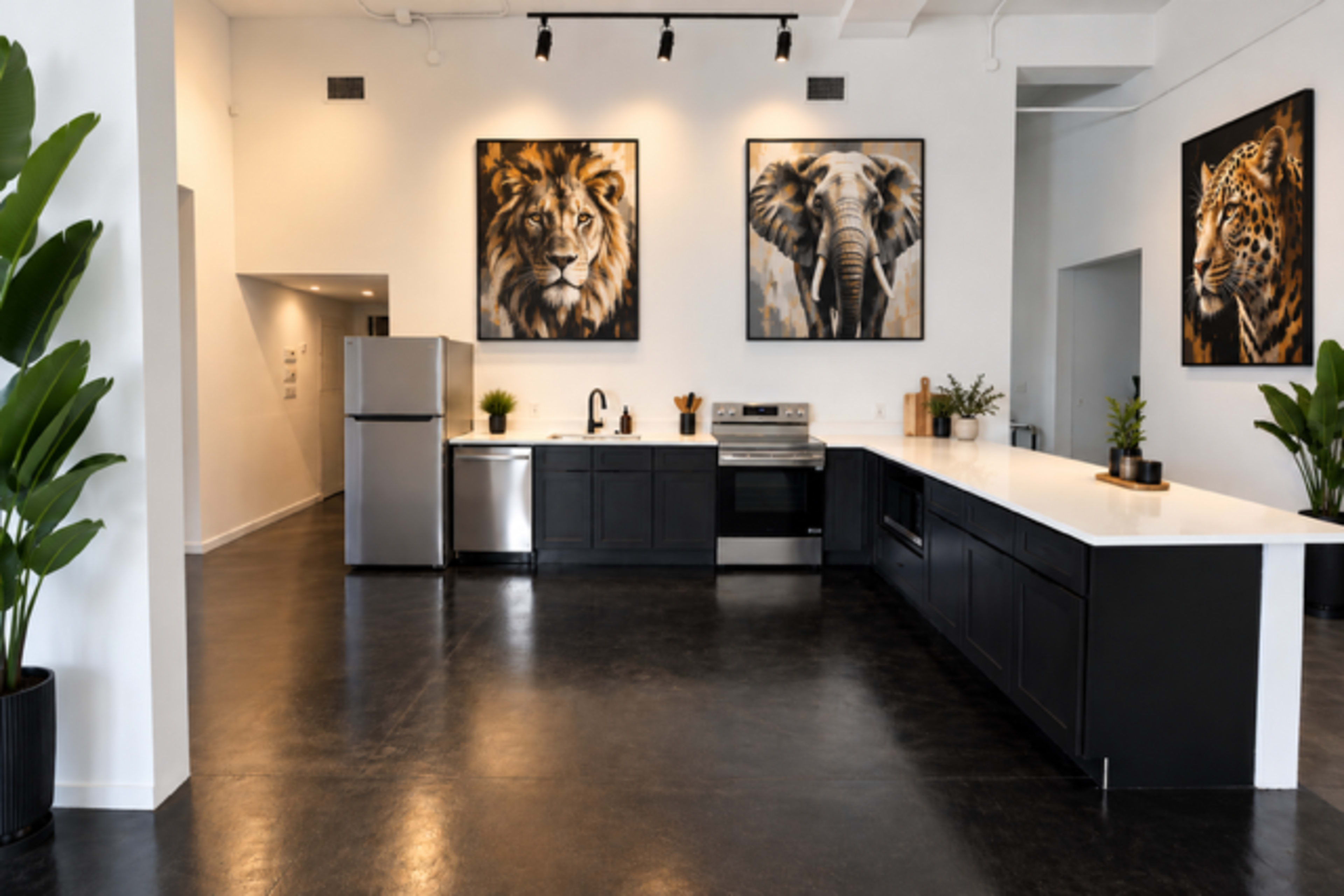 The image shows a modern kitchen with stainless steel appliances, a large island, and three animal-themed paintings on the walls.