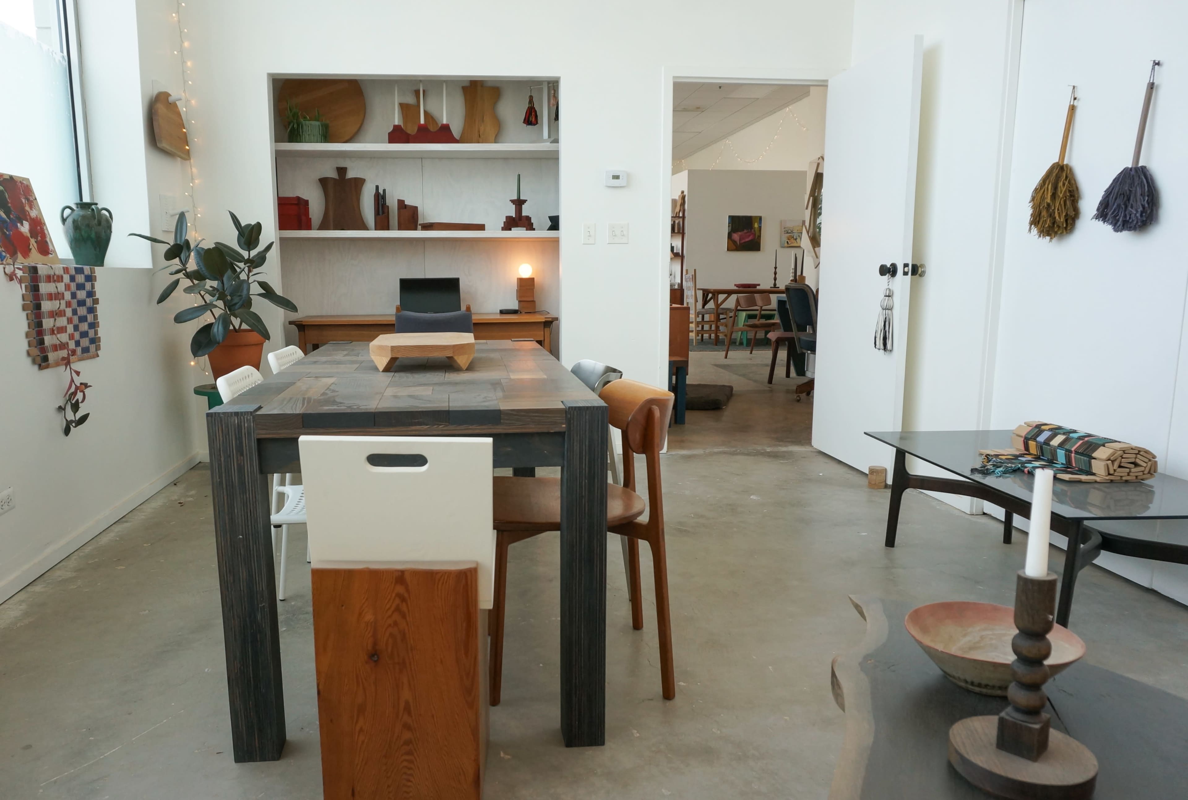 The image features a modern interior with a dining table surrounded by various chairs, showcasing minimalistic decor and open spaces.