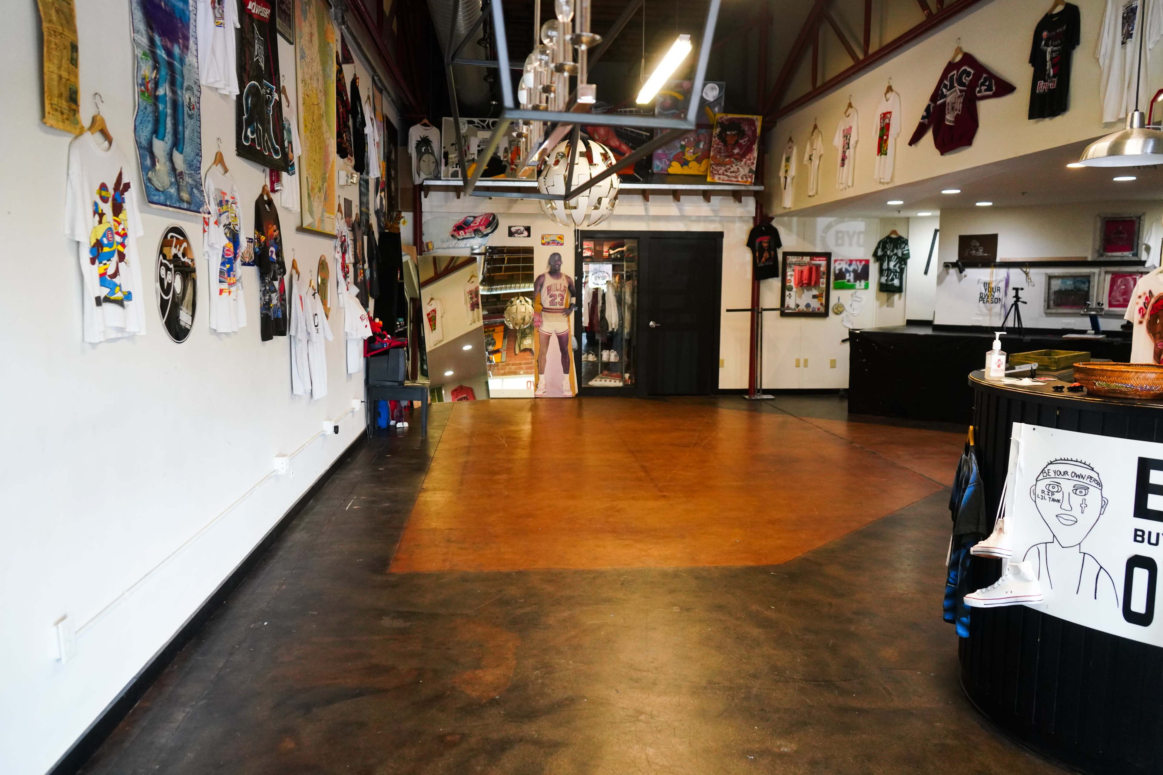 An indoor space featuring a polished floor, various murals and artwork on the walls, and merchandise display areas.