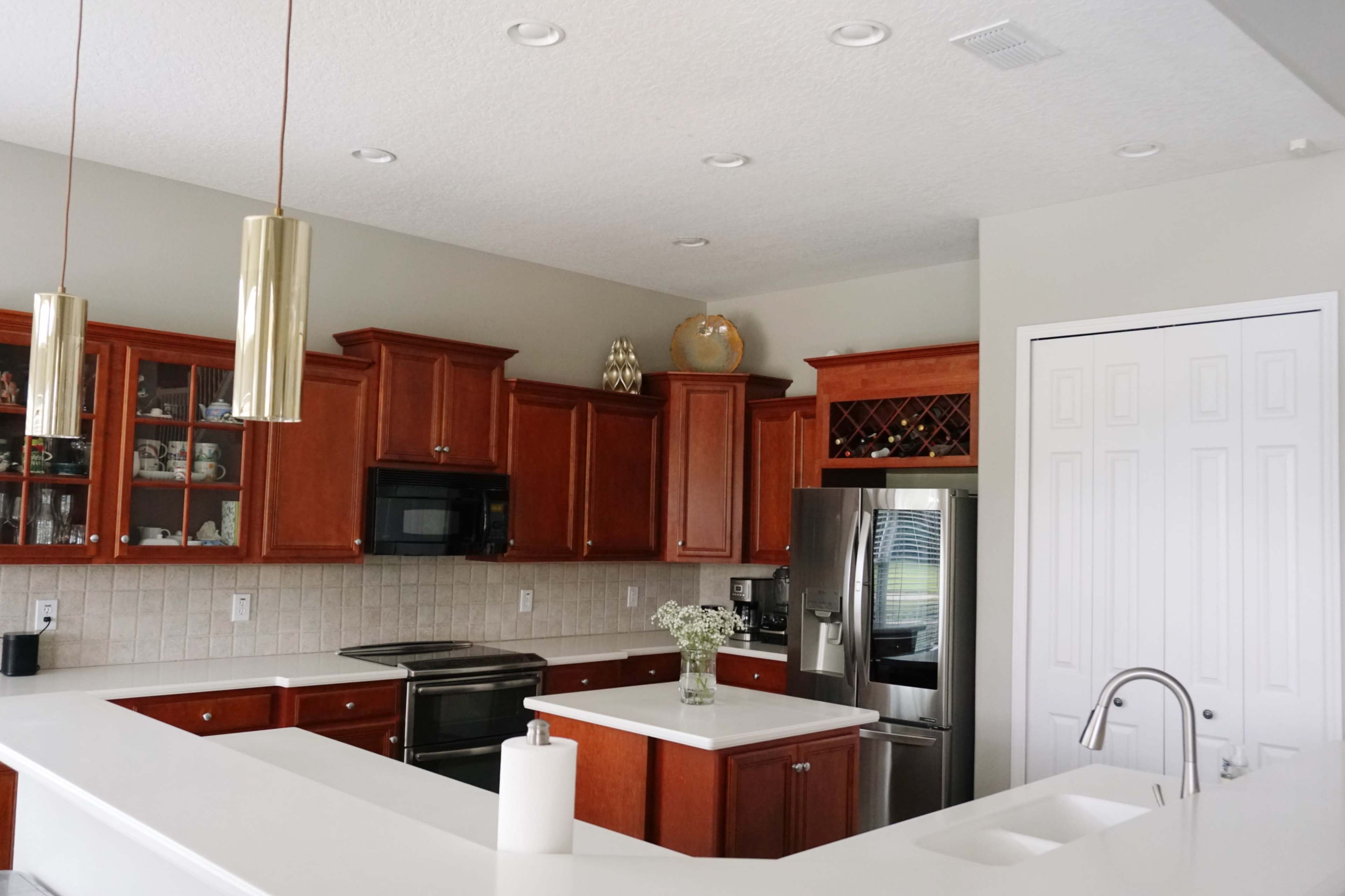A modern kitchen features wooden cabinetry, stainless steel appliances, and a white countertop with a sink.