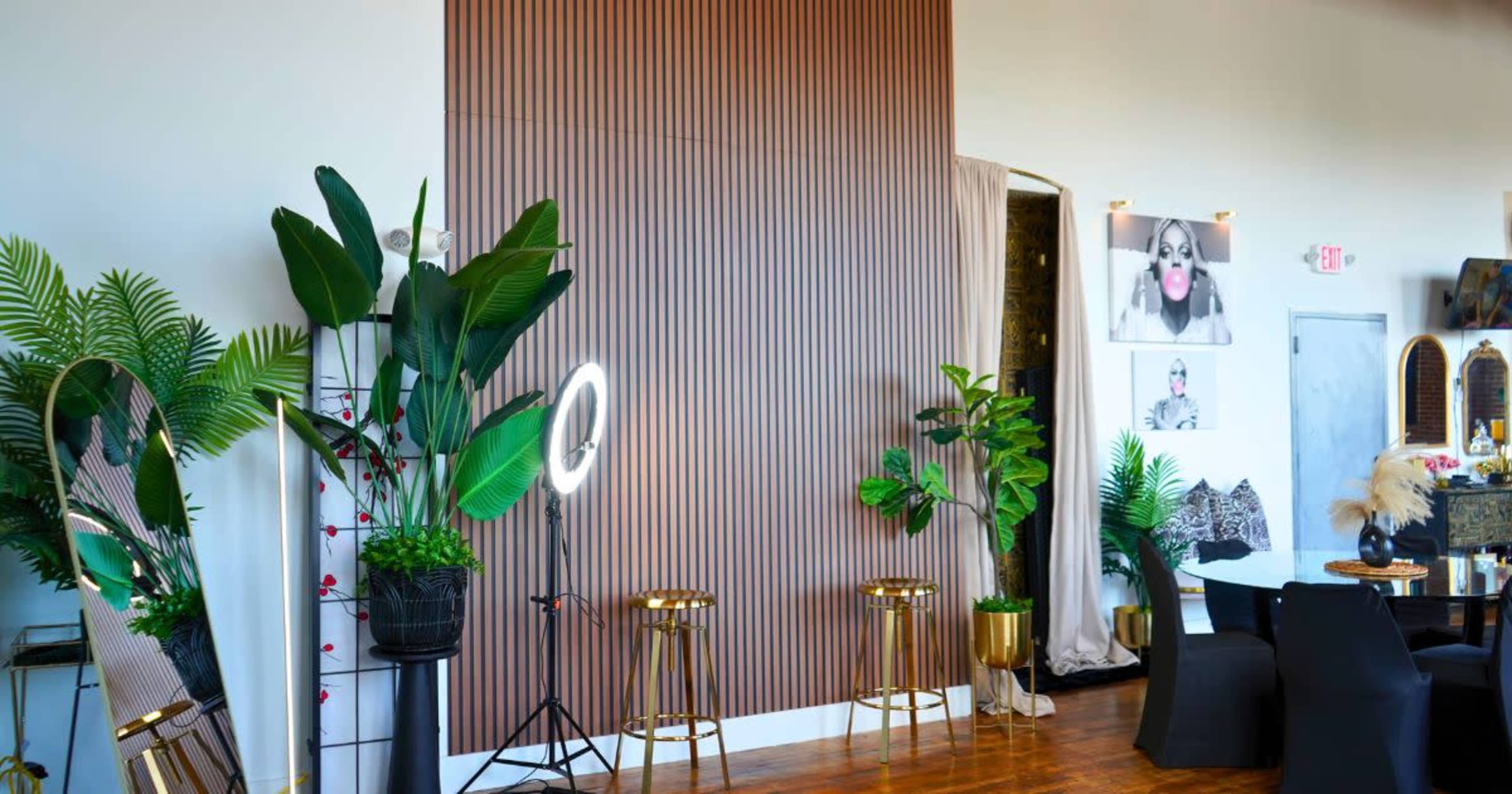 The image shows a stylish interior of a salon featuring wooden wall panels, greenery, decorative mirrors, and seating arrangements.