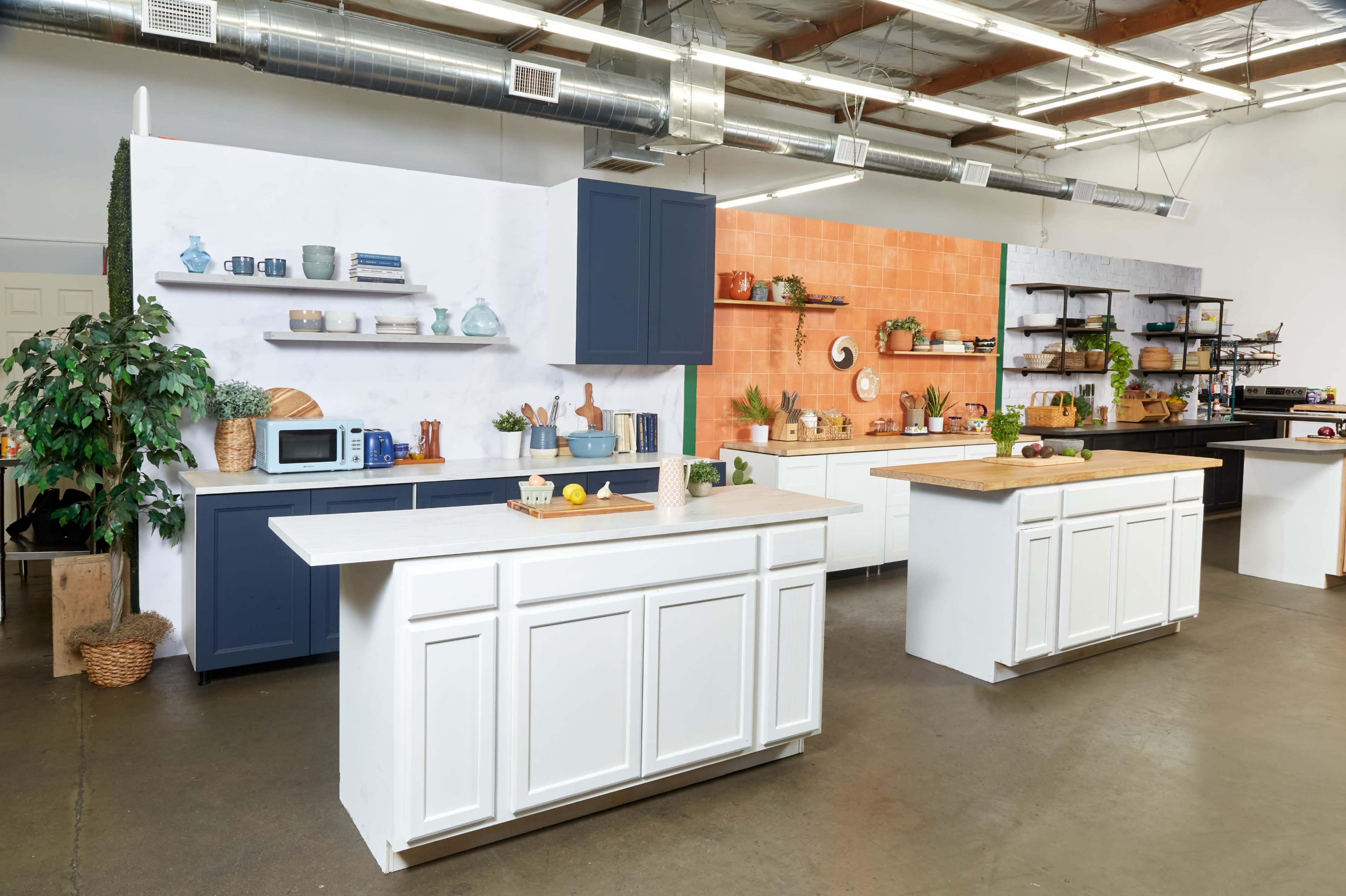A modern kitchen setup with white cabinetry, wooden countertops, and various kitchen items displayed on shelves and countertops.