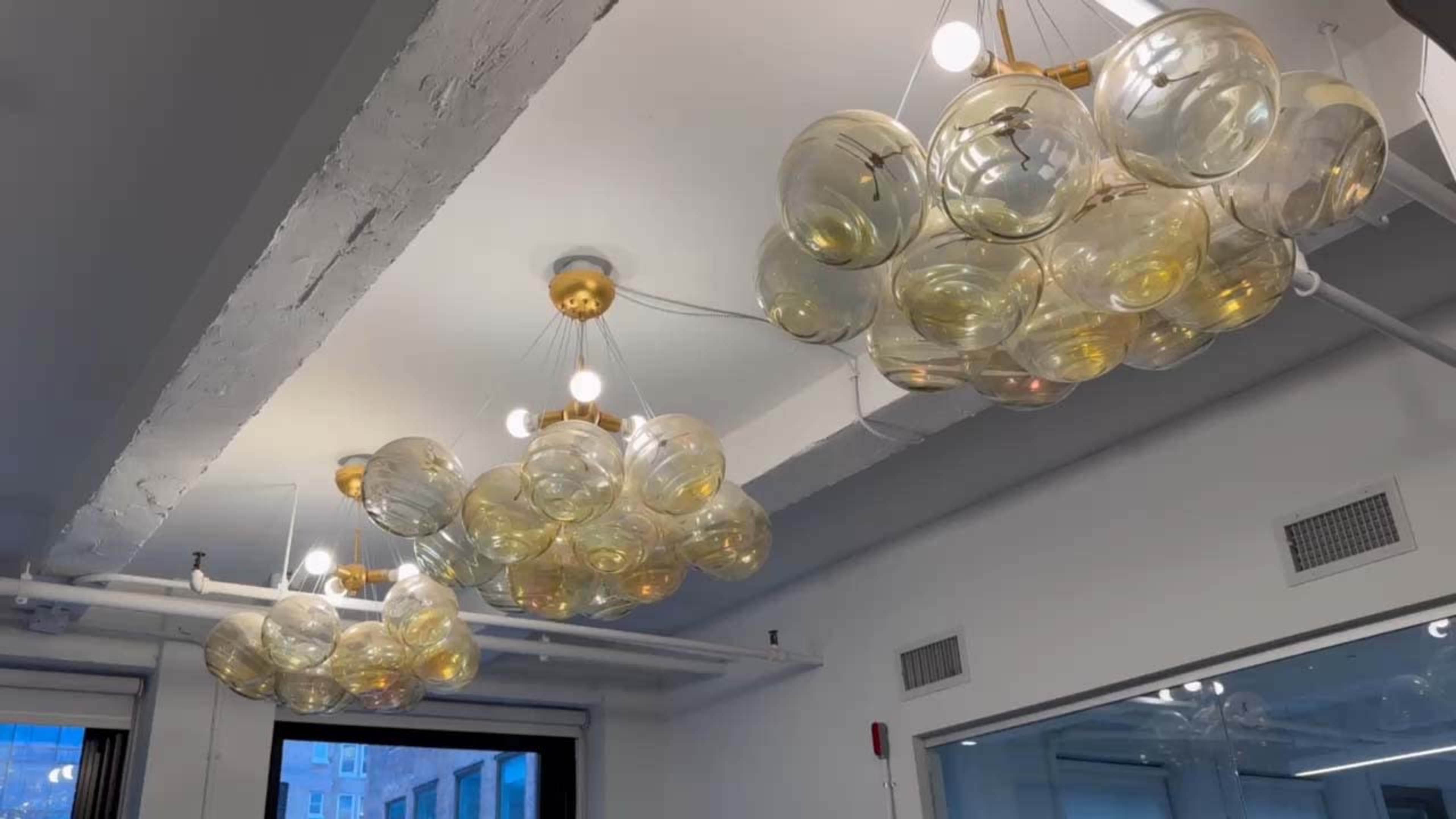 The image shows a modern ceiling light fixture composed of multiple clear glass globes arranged in a cloud-like formation.