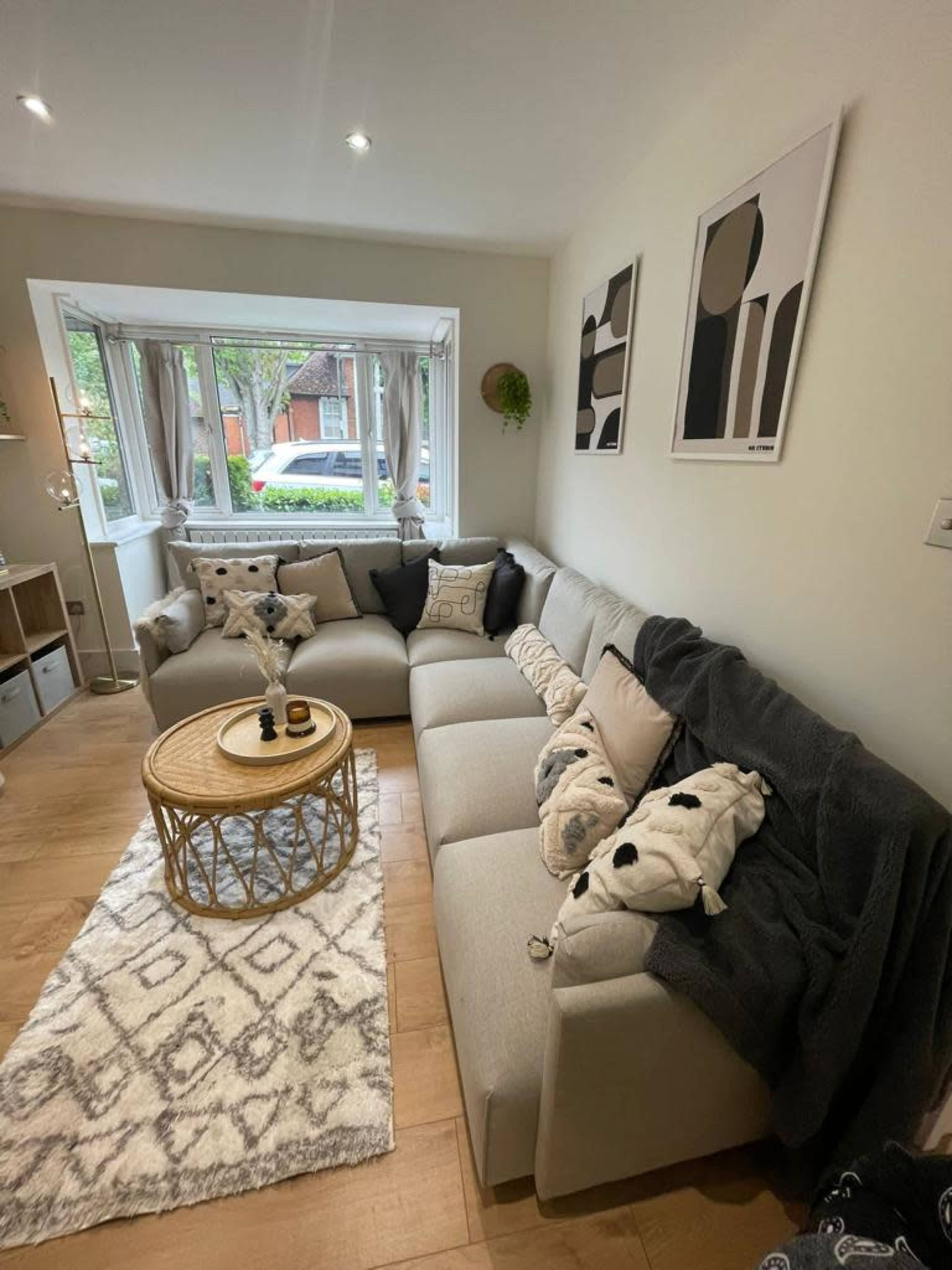 A modern living room features a sectional sofa, a round coffee table, and decorative throws on a patterned rug.