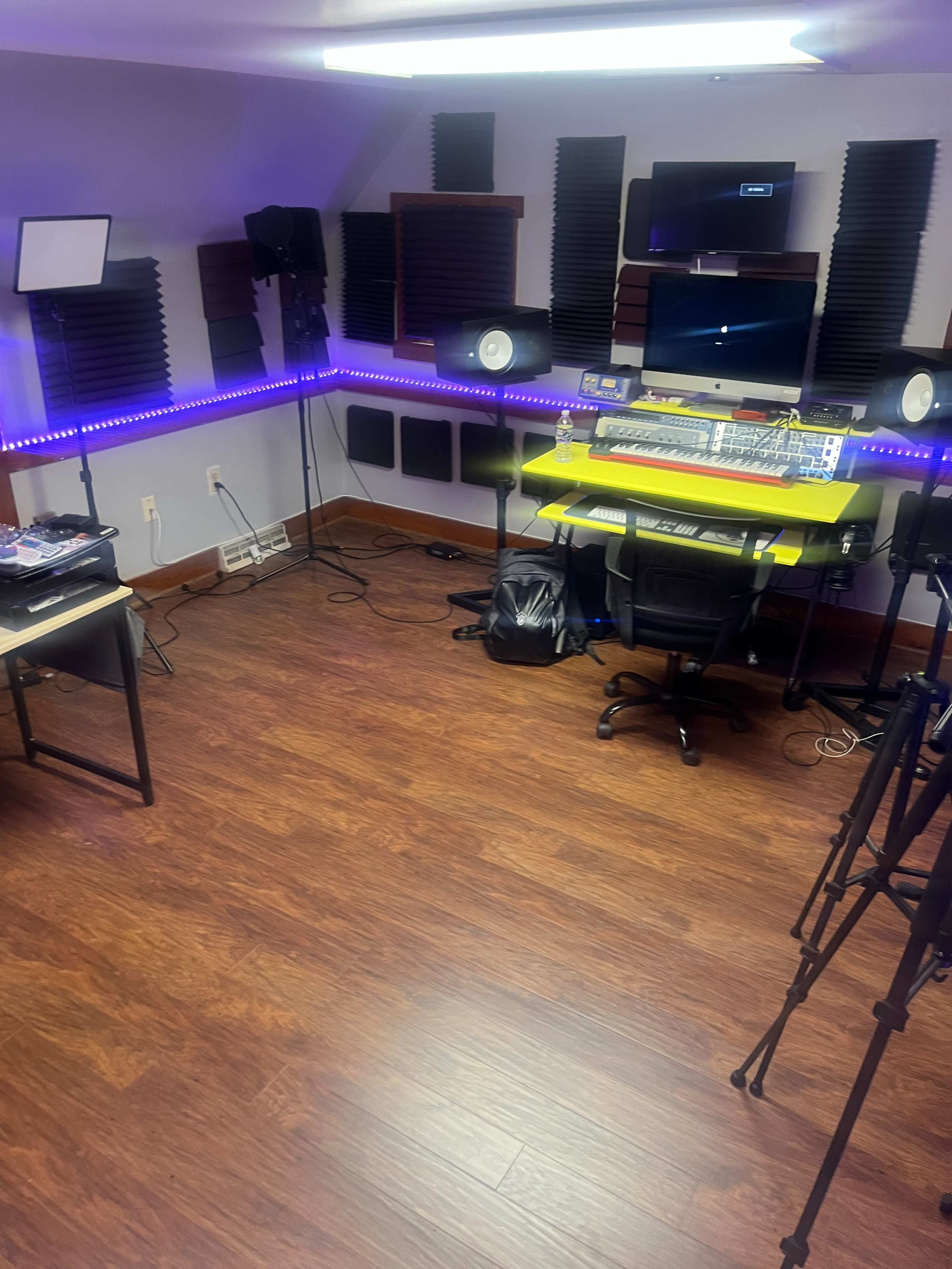 A music studio with a mixing console, speakers, and LED lighting along the walls.