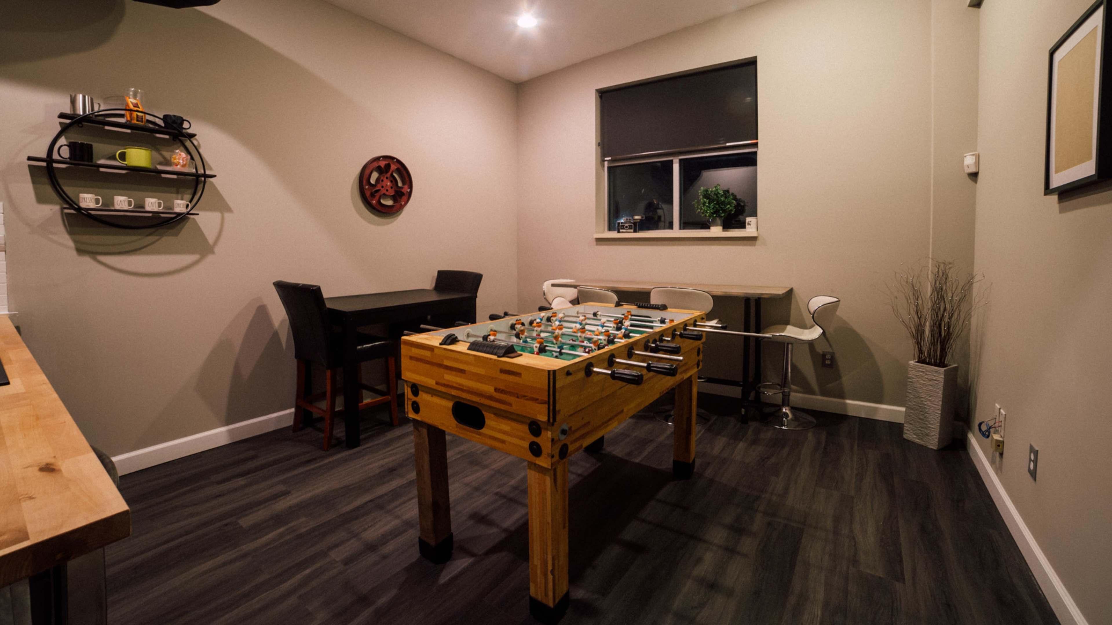A foosball table is set up in a small room with two seating areas and minimal decor.