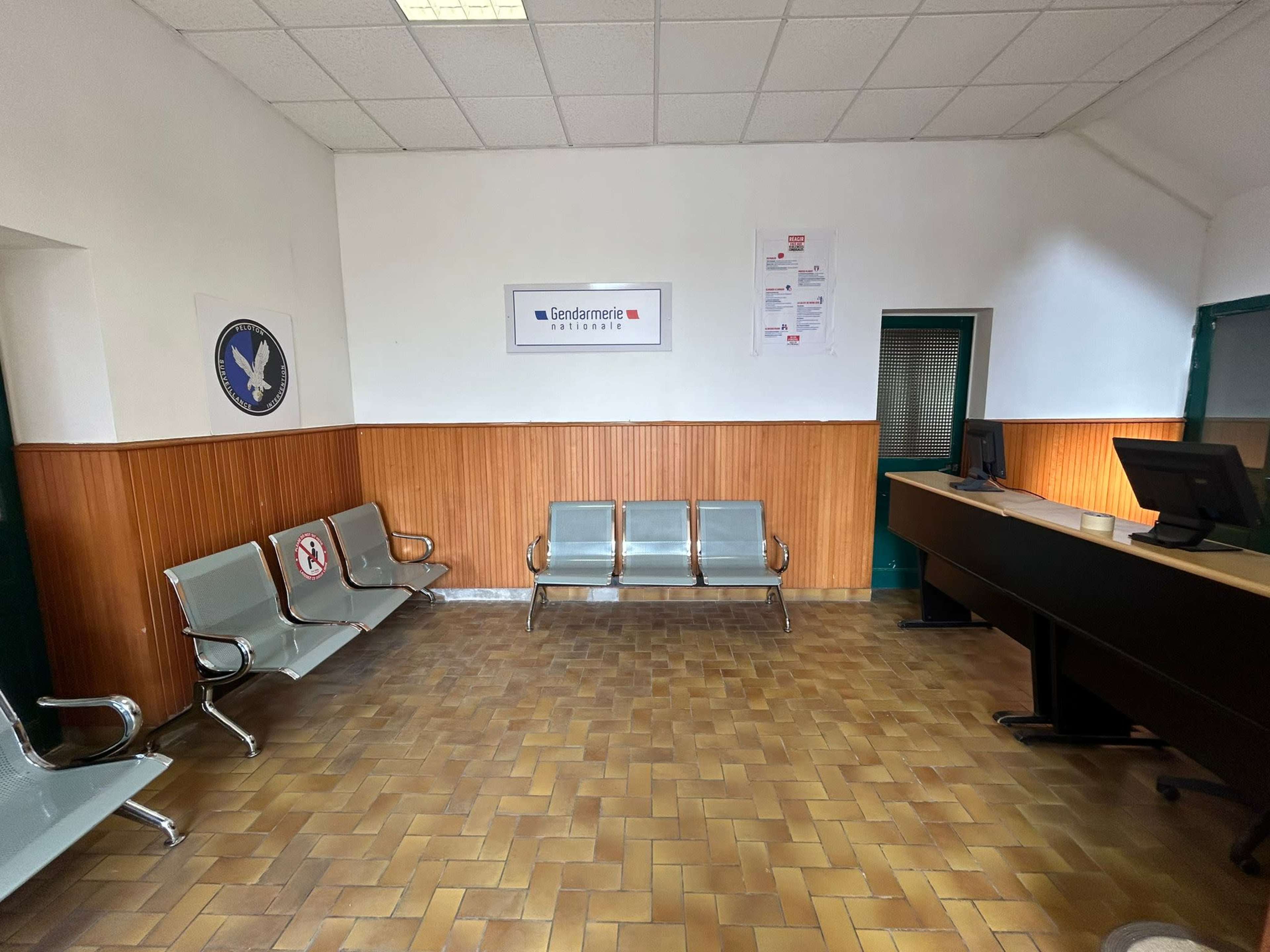 A waiting area with metallic benches, a reception desk, and wooden paneling on the walls.