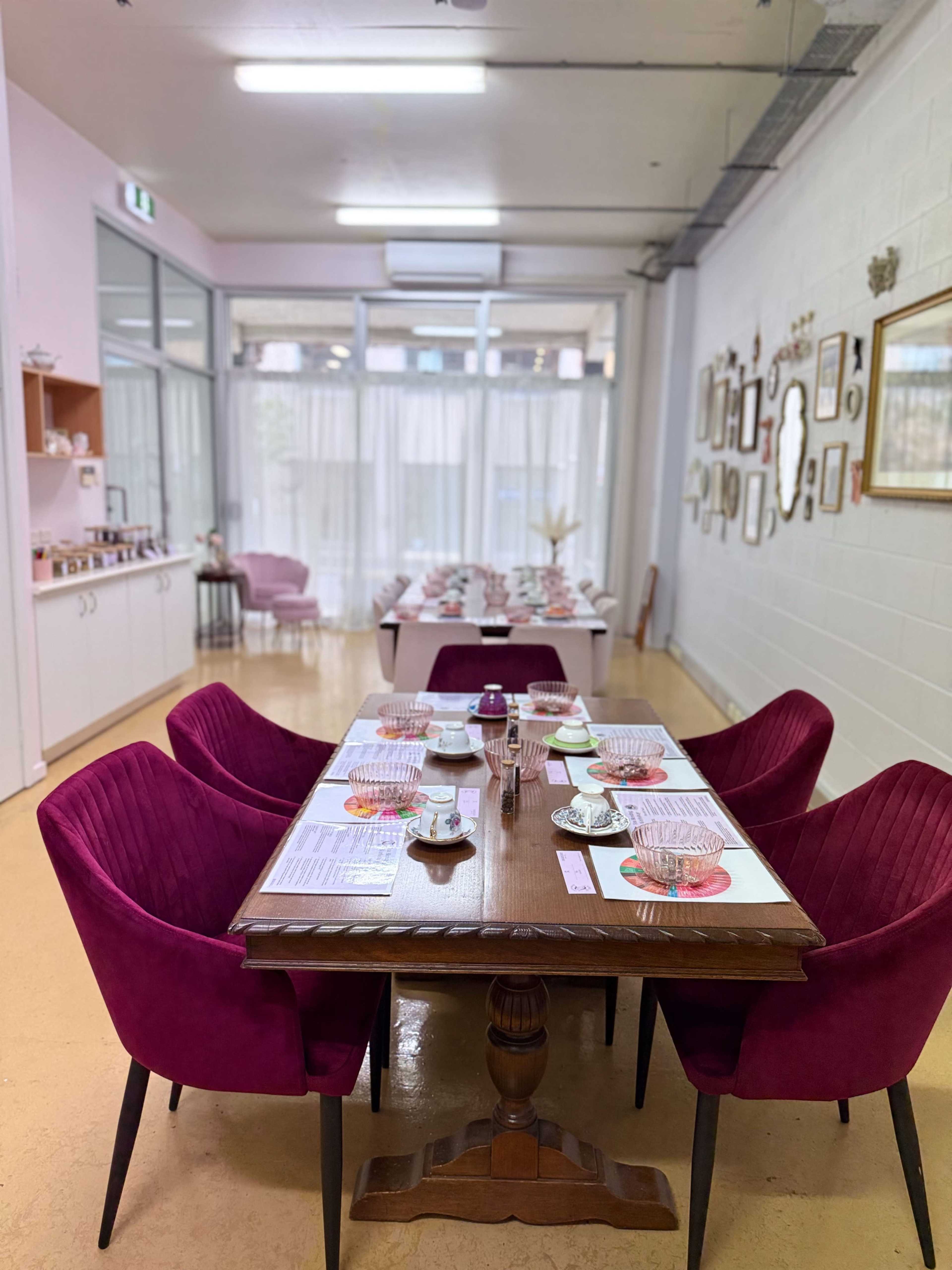 A dining area features a wooden table set with plates and cutlery, surrounded by plush purple chairs, while a softly lit room is adorned with various framed pictures on the walls.
