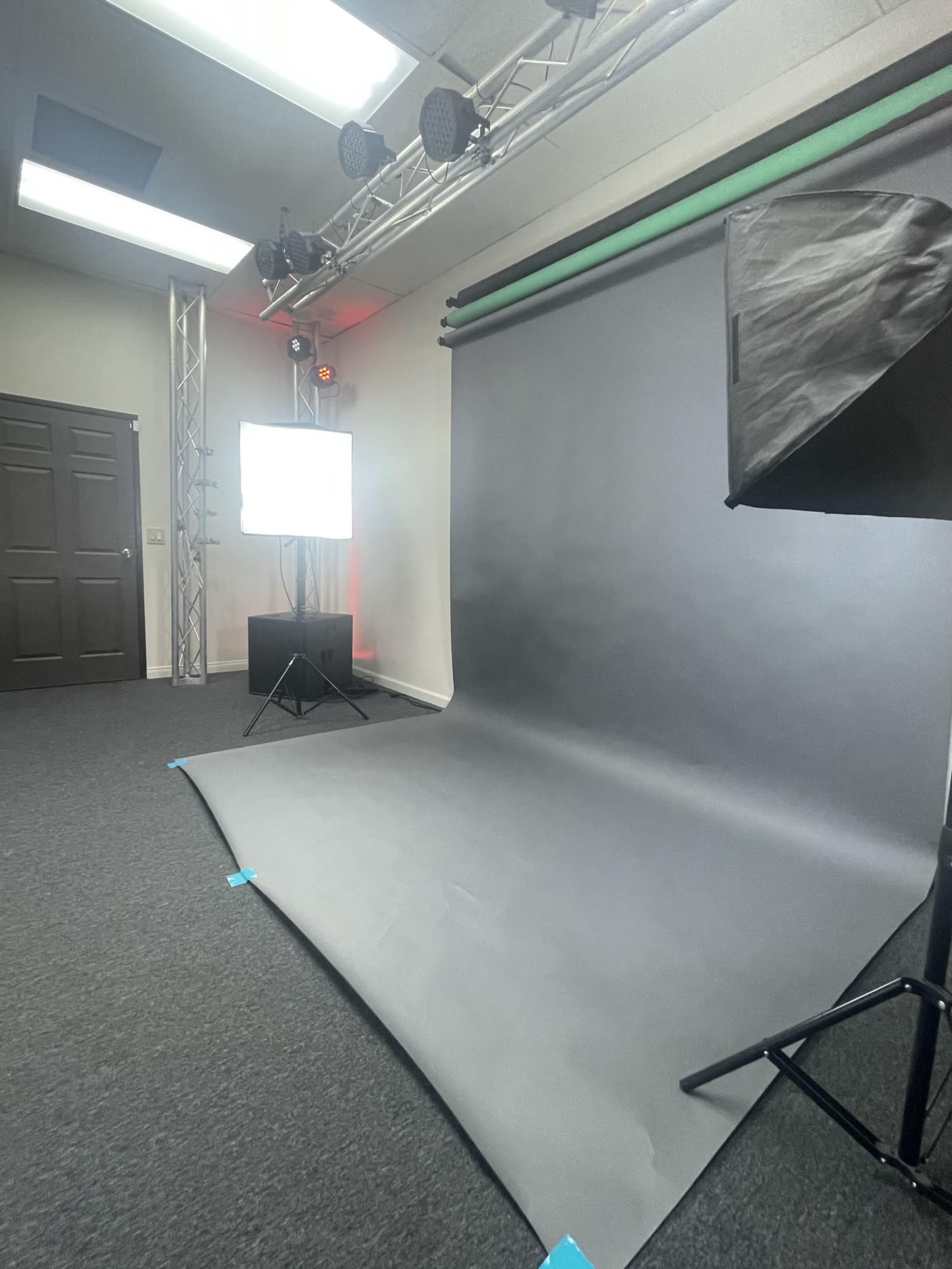 A photography studio setup featuring a gray backdrop, lighting equipment, and a monitor.