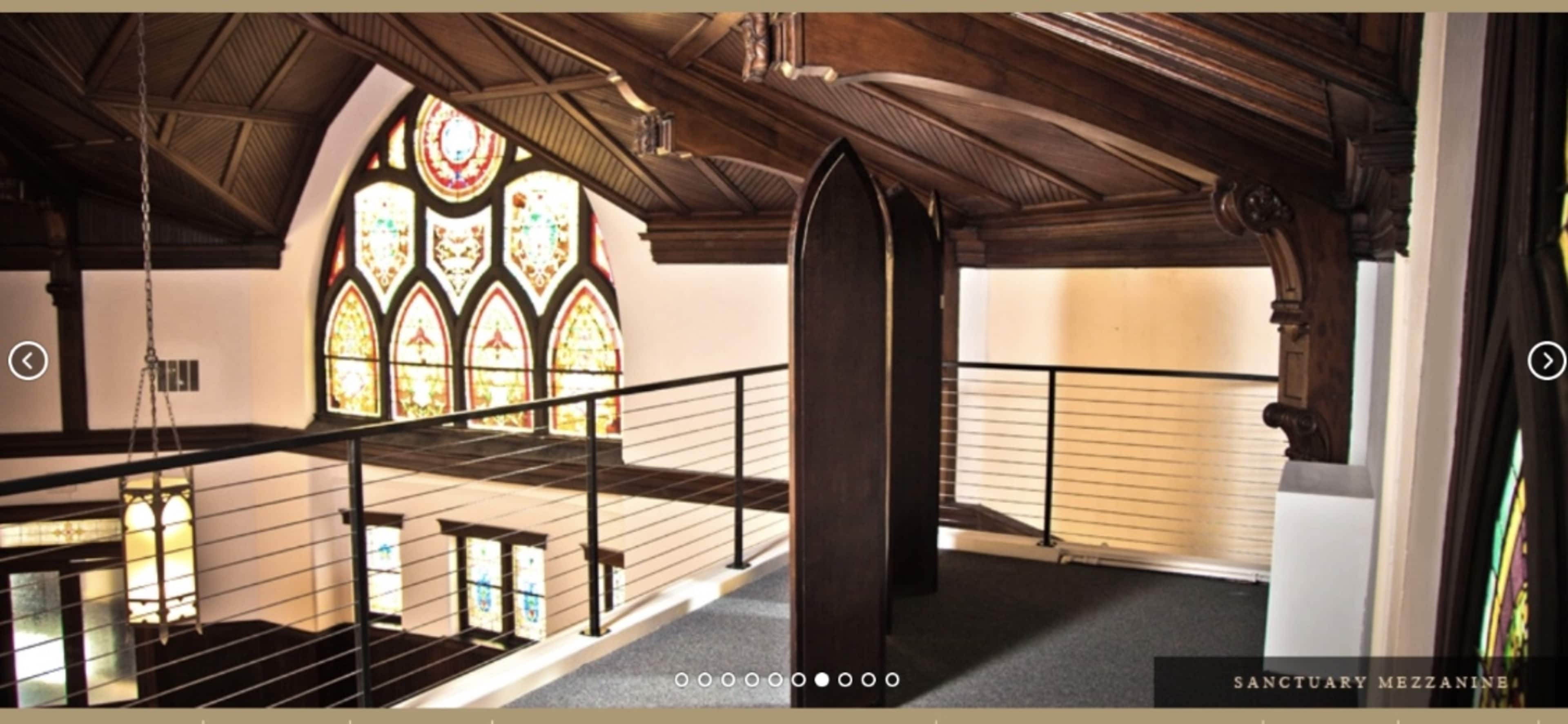 A mezzanine level in a building with wooden beams and stained glass windows visible in the background.