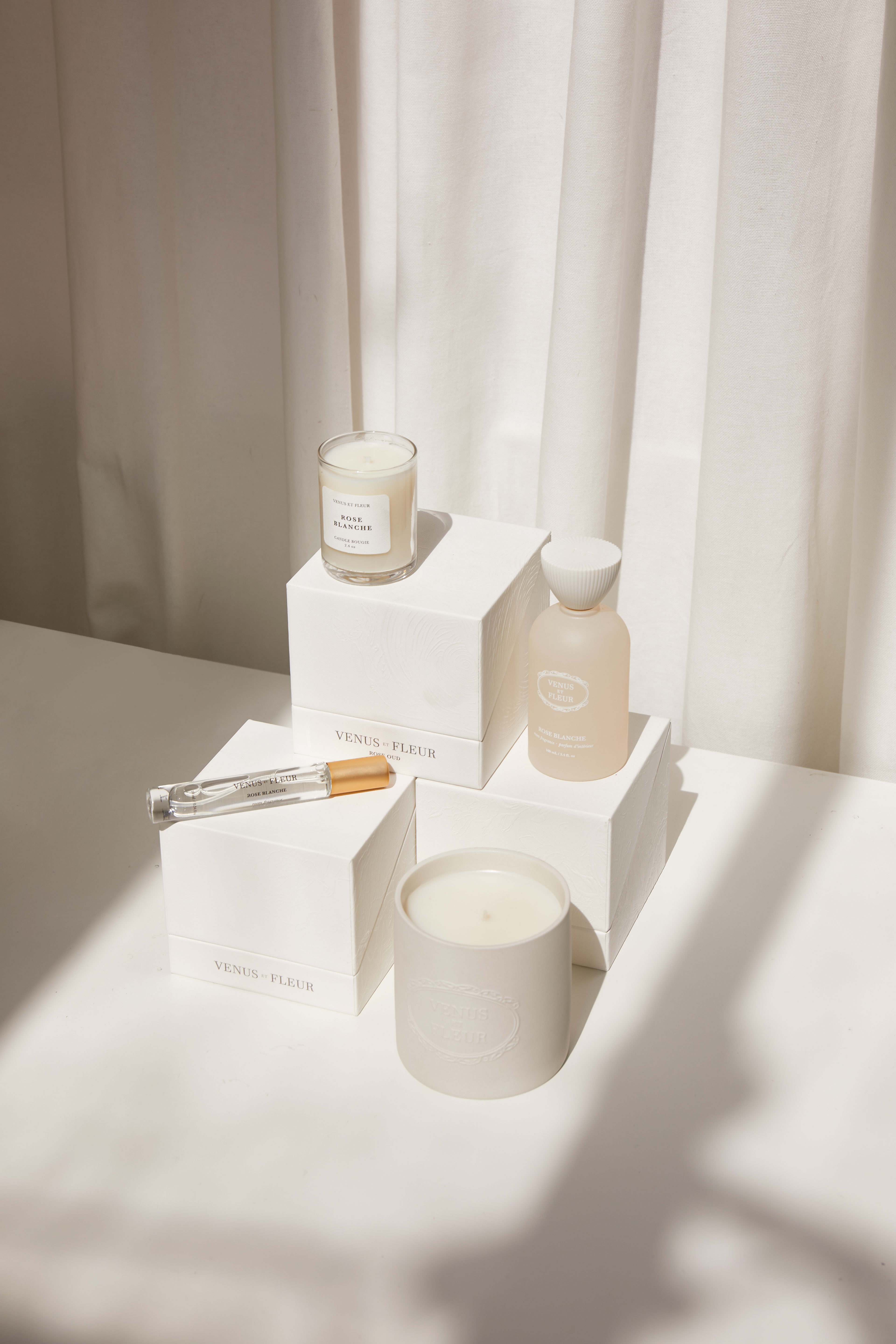 A minimal product photoshoot featuring a white candle and holder paired with a box on a table.