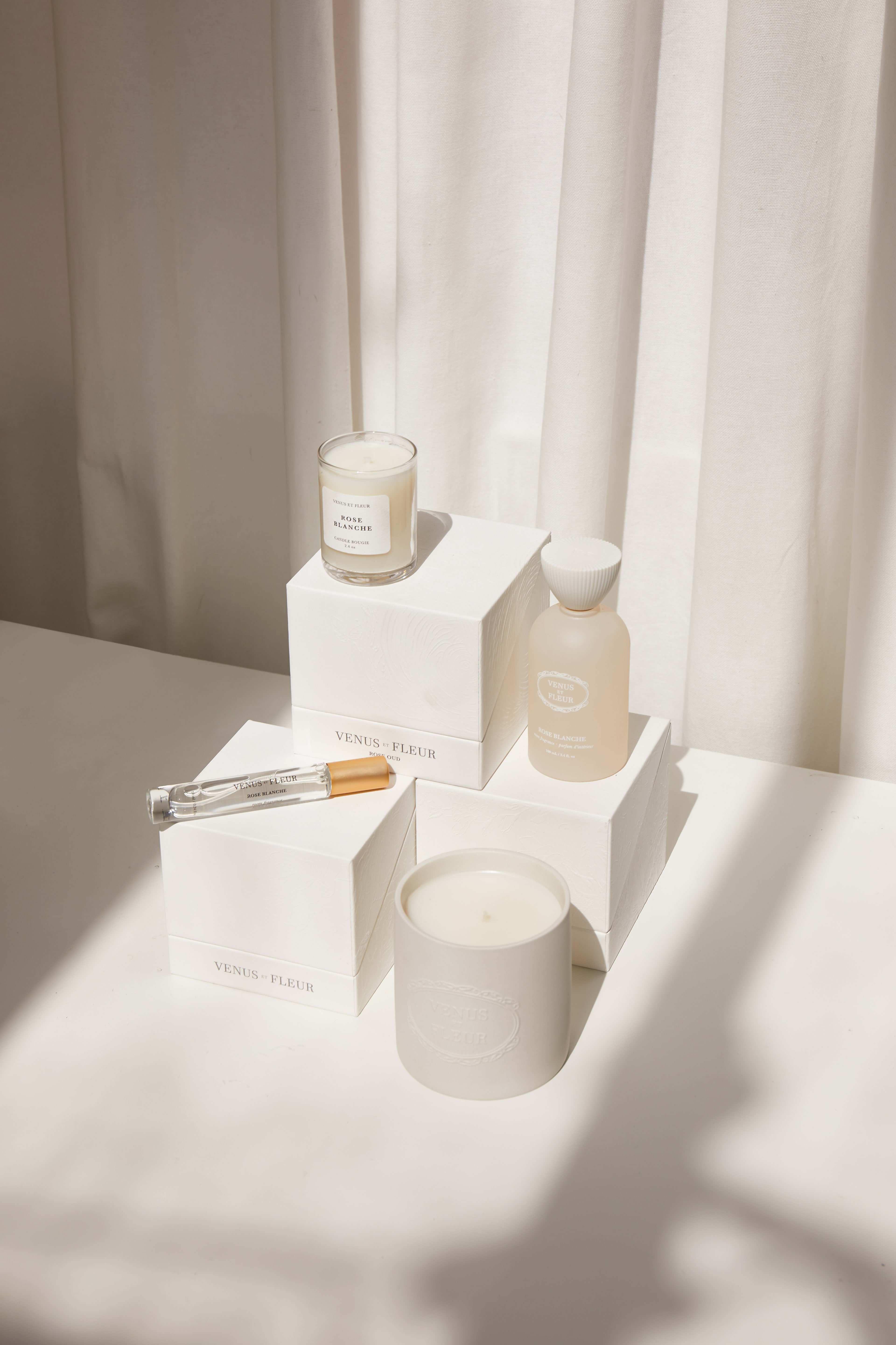 A minimal product photo shoot featuring a white candle and holder paired with a box on a table.