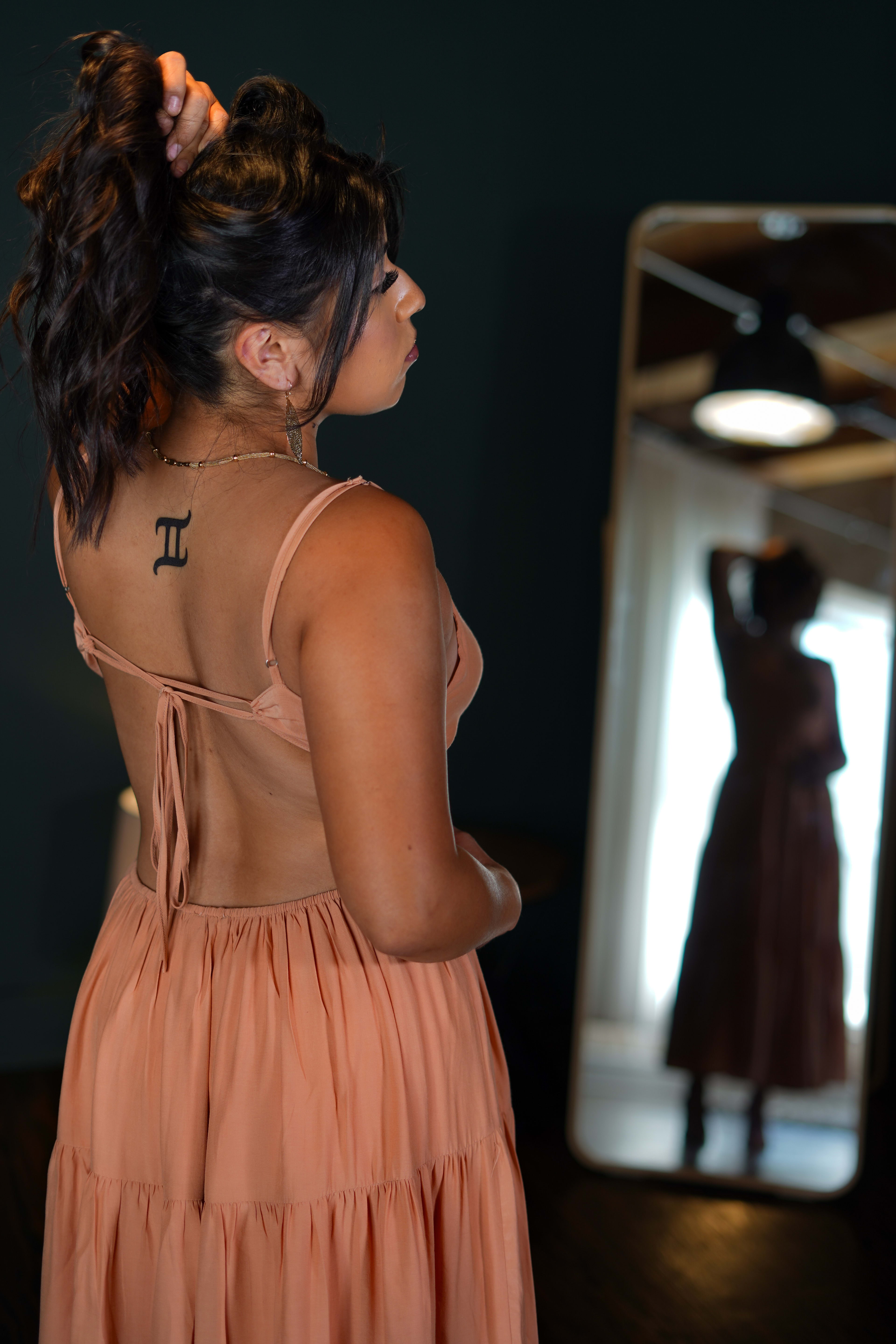 Une femme avec un tatouage dans le dos et dans une robe orange pour un shooting photo de mode.