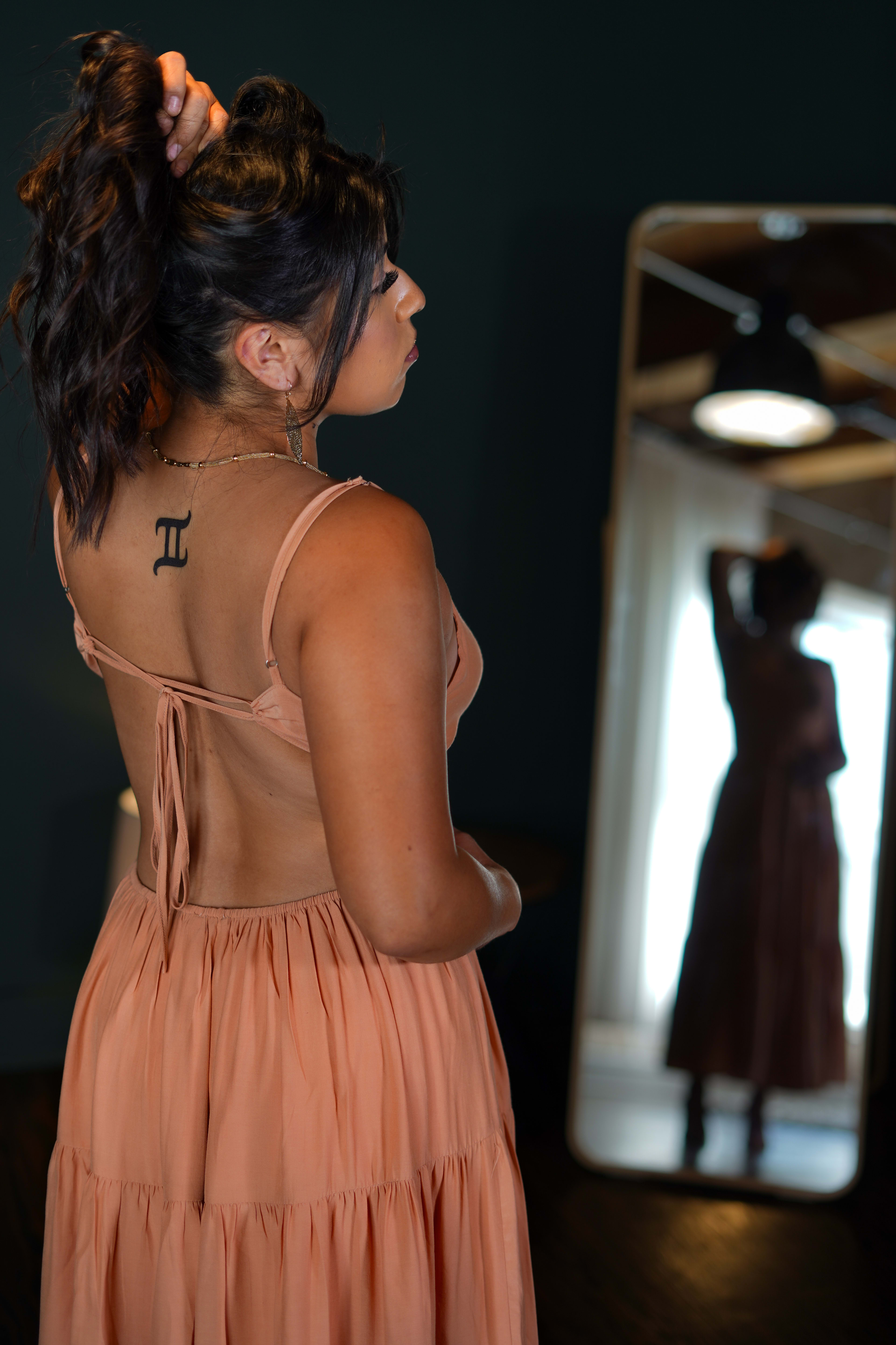 Eine Frau mit einer Tätowierung auf dem Rücken in einem orangefarbenen Kleid für ein Mode-Fotoshooting.