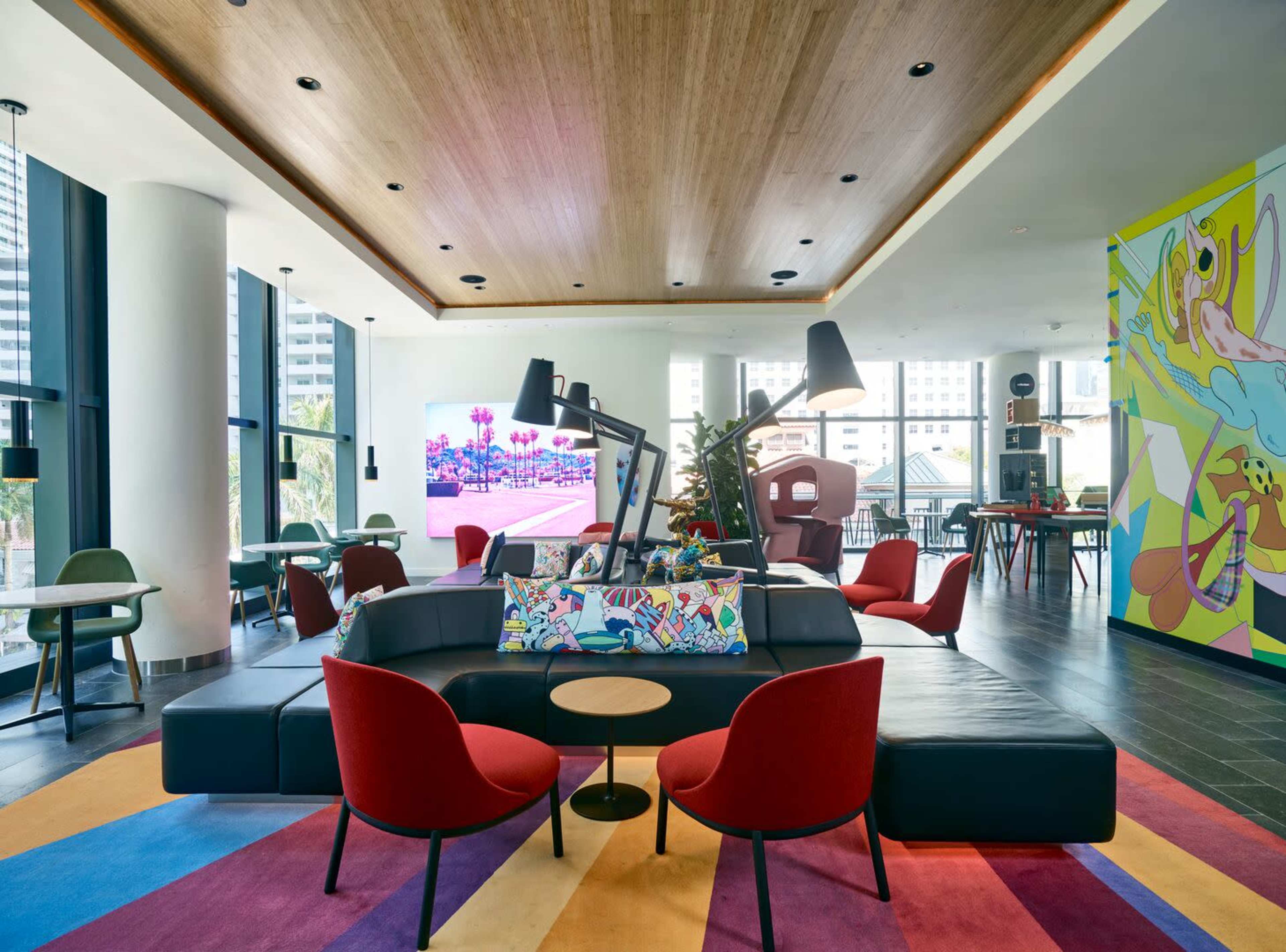 A modern lounge area with colorful furniture, large lamps, and a vibrant mural on the wall.