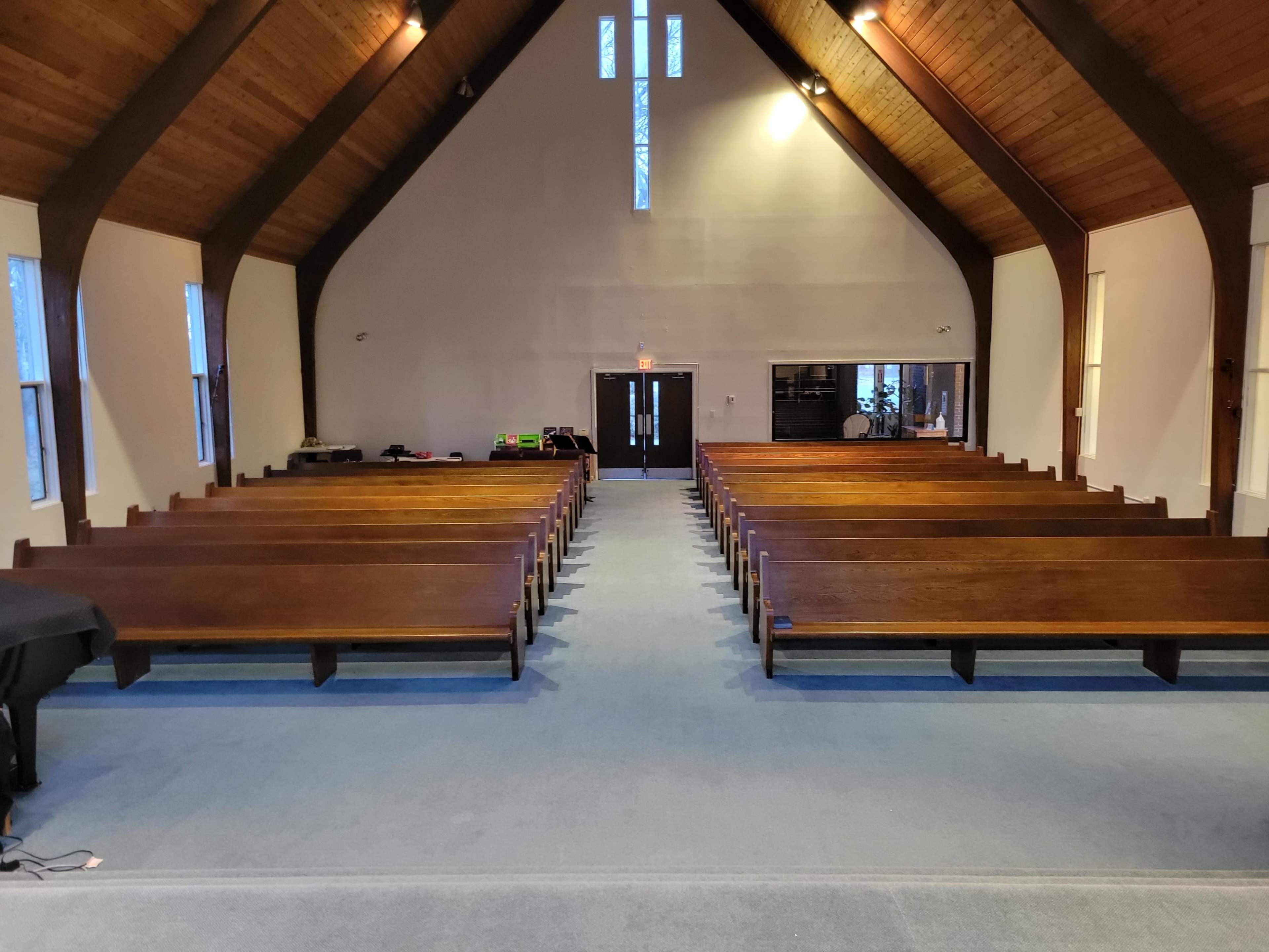 The interior of a church with wooden pews arranged in rows facing a central altar area.