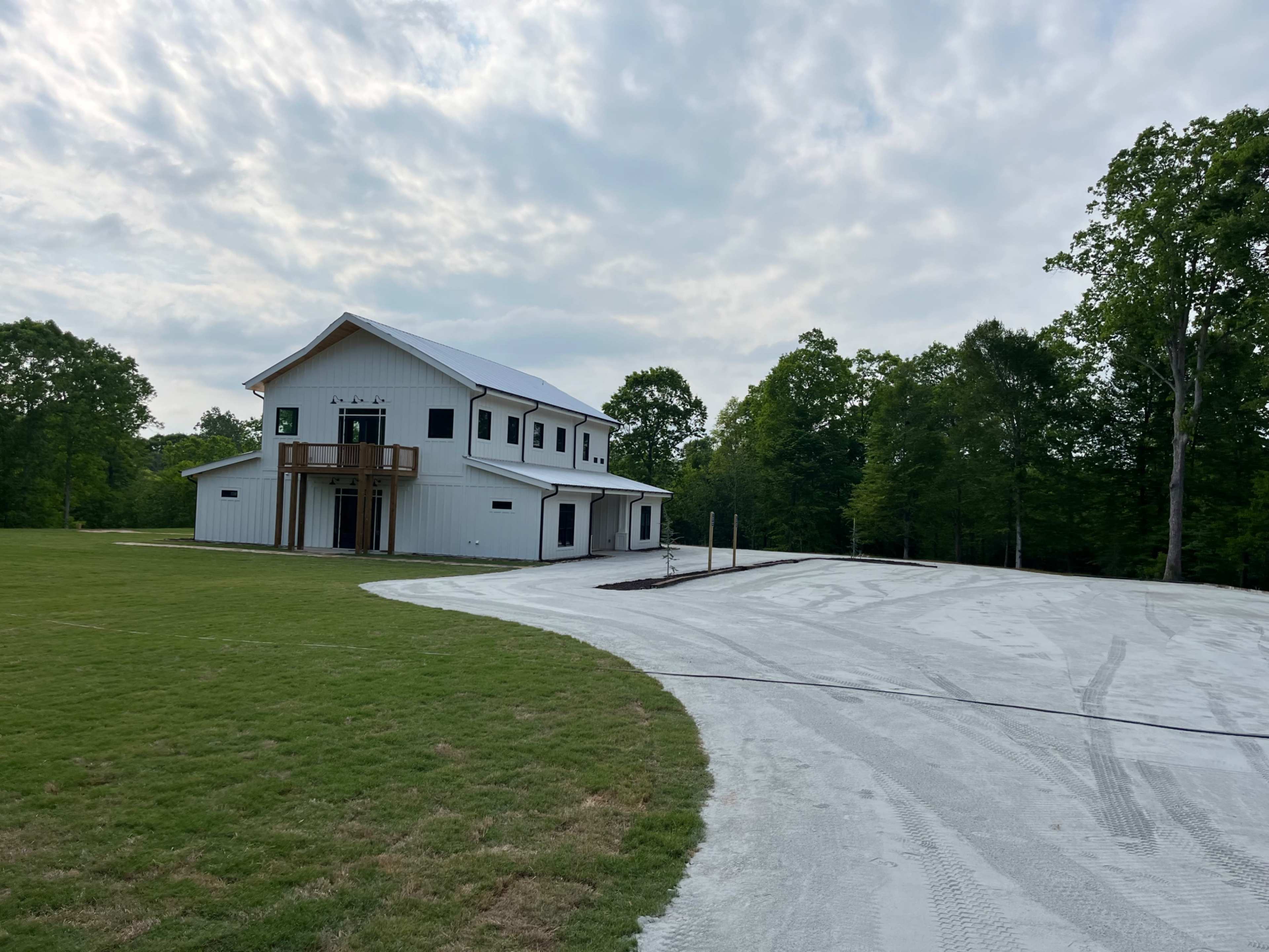 A modern two-story white building sits on a large, cleared lot with freshly paved gravel extending around it.