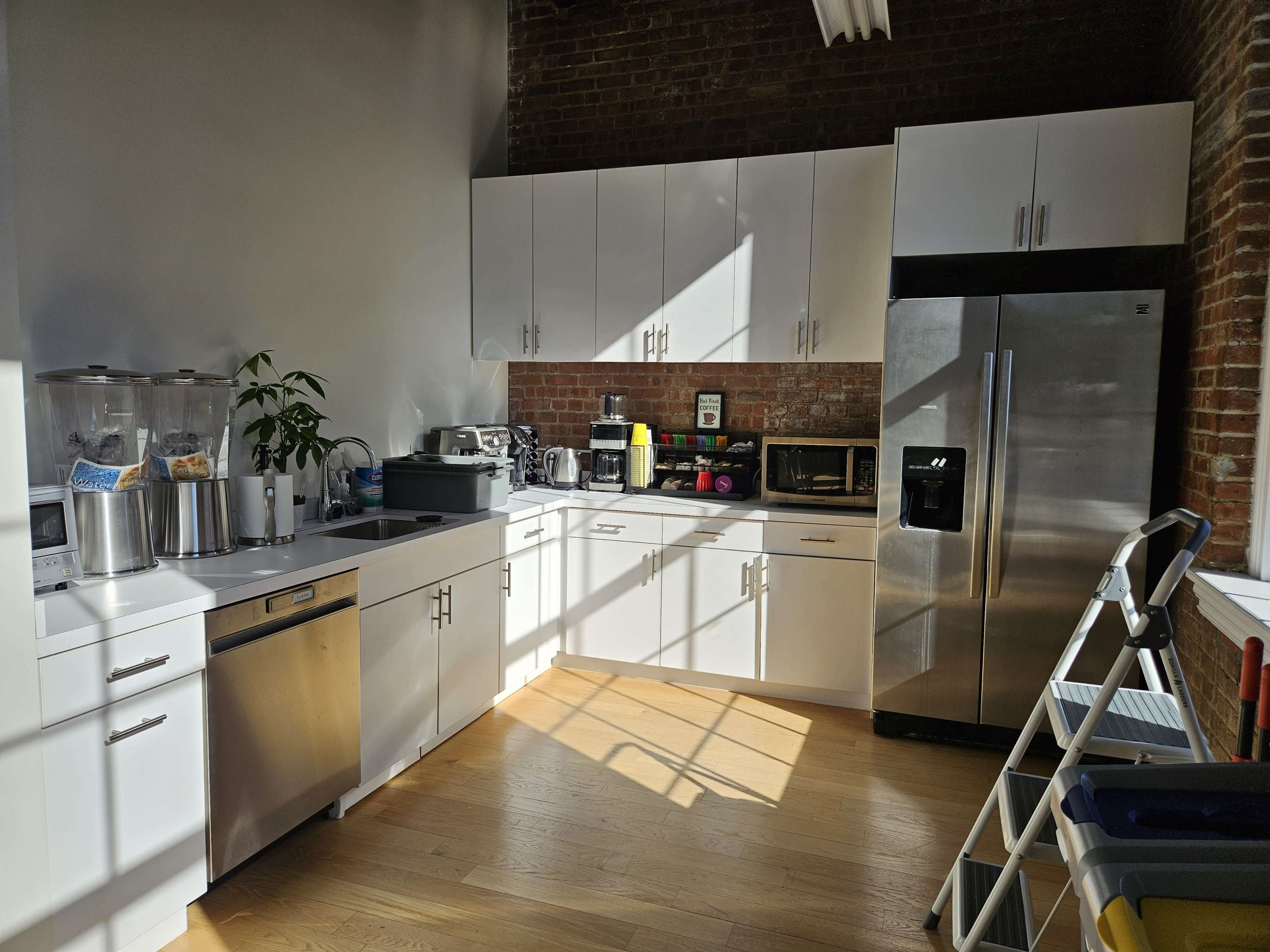 The kitchen features white cabinets, stainless steel appliances, and large windows allowing natural light to illuminate the space.